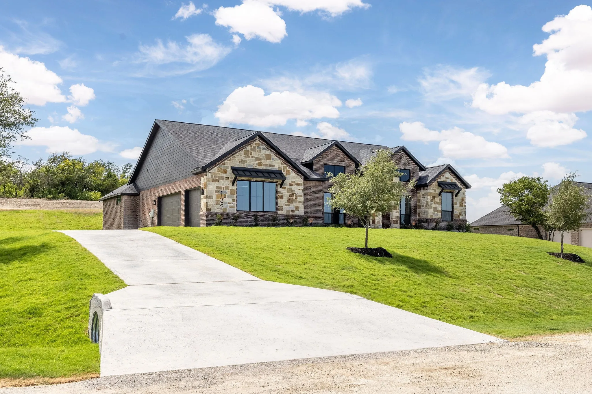 Stone and brick facade residence featuring a steep-pitched shingle roof and a multi-car garage