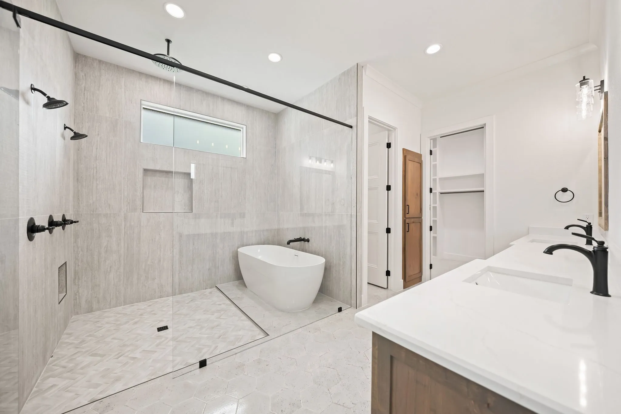 Spacious bathroom featuring a freestanding tub, walk-in shower with dual showerheads, and a dual-sink vanity with white countertops