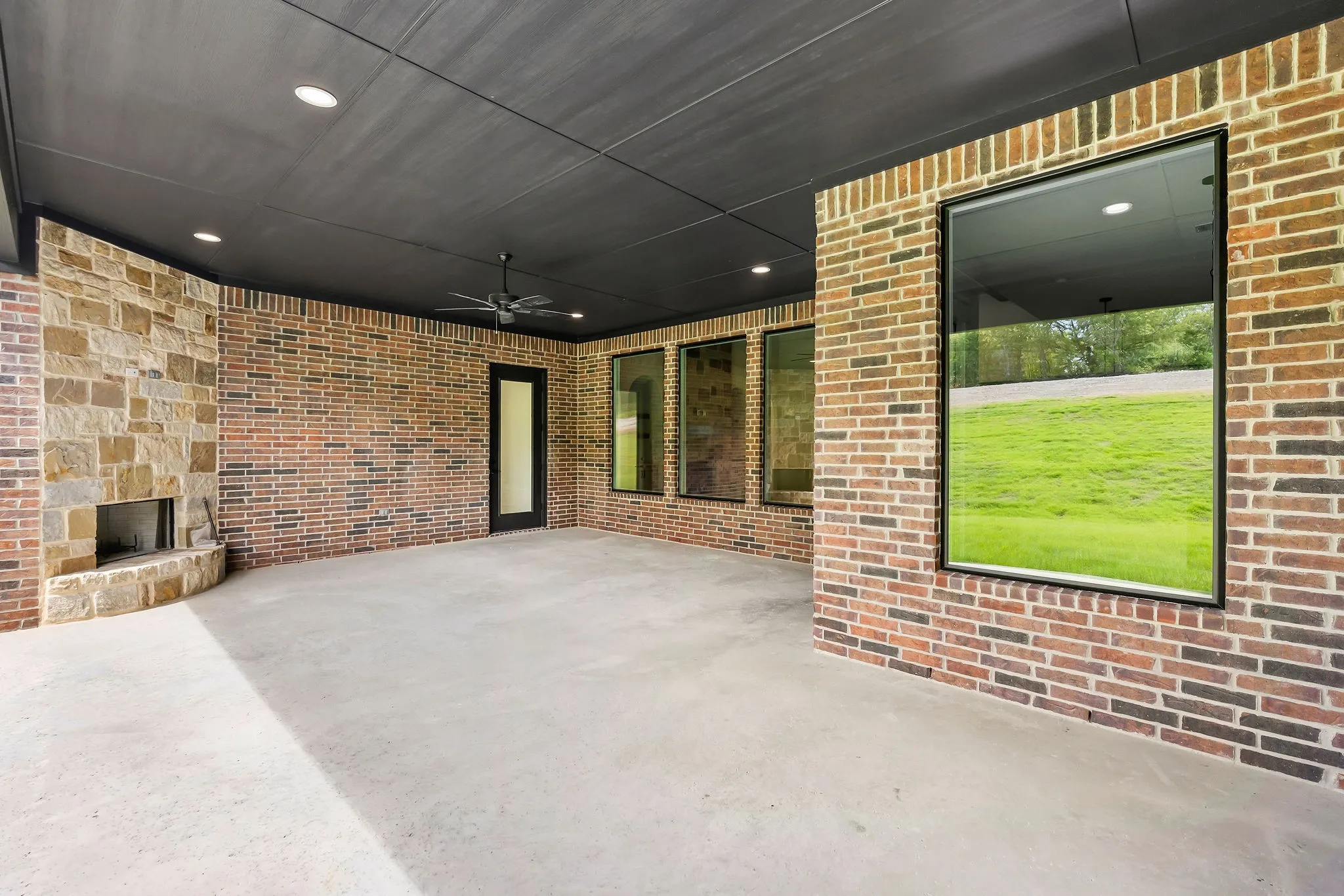 Expansive covered patio featuring a stone fireplace, recessed lighting, and a ceiling fan