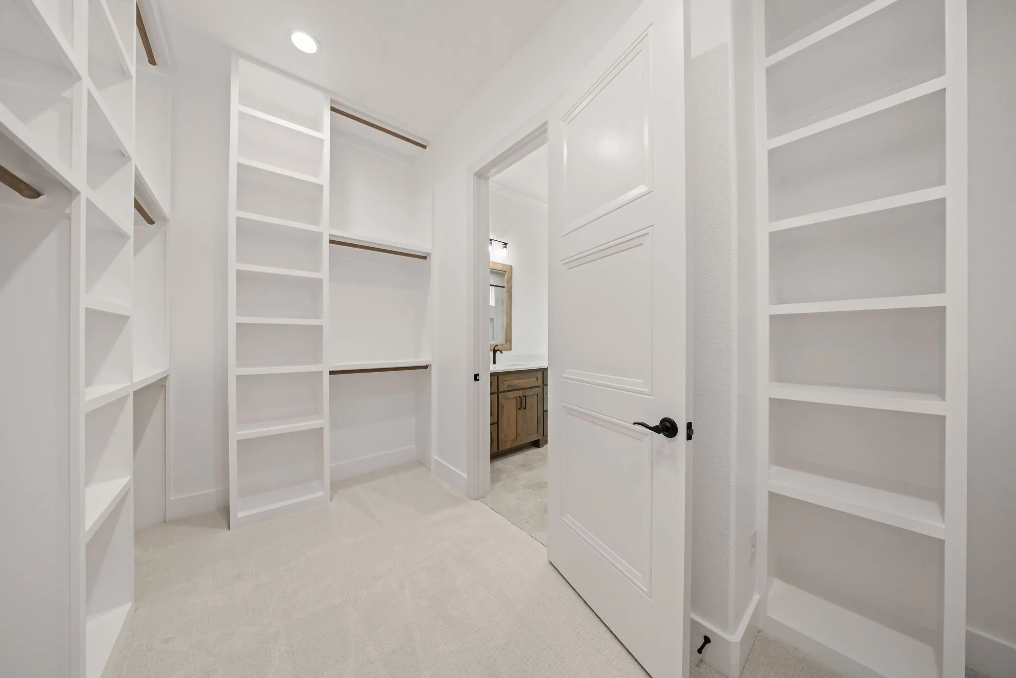 Custom closet featuring extensive built-in shelving, multiple hanging rods, and soft carpet flooring