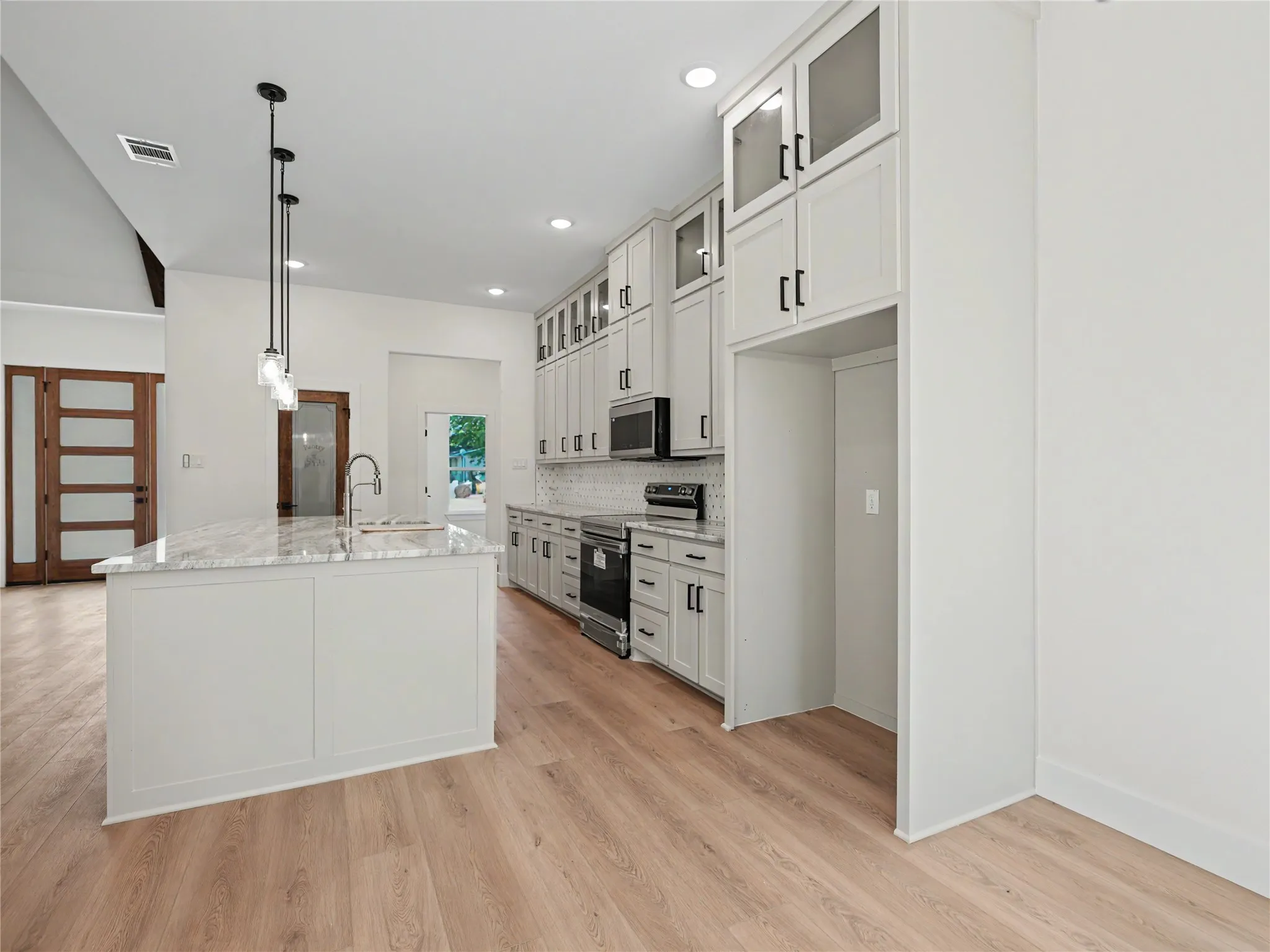 Modern kitchen featuring a central island with a sink and a light-toned countertop