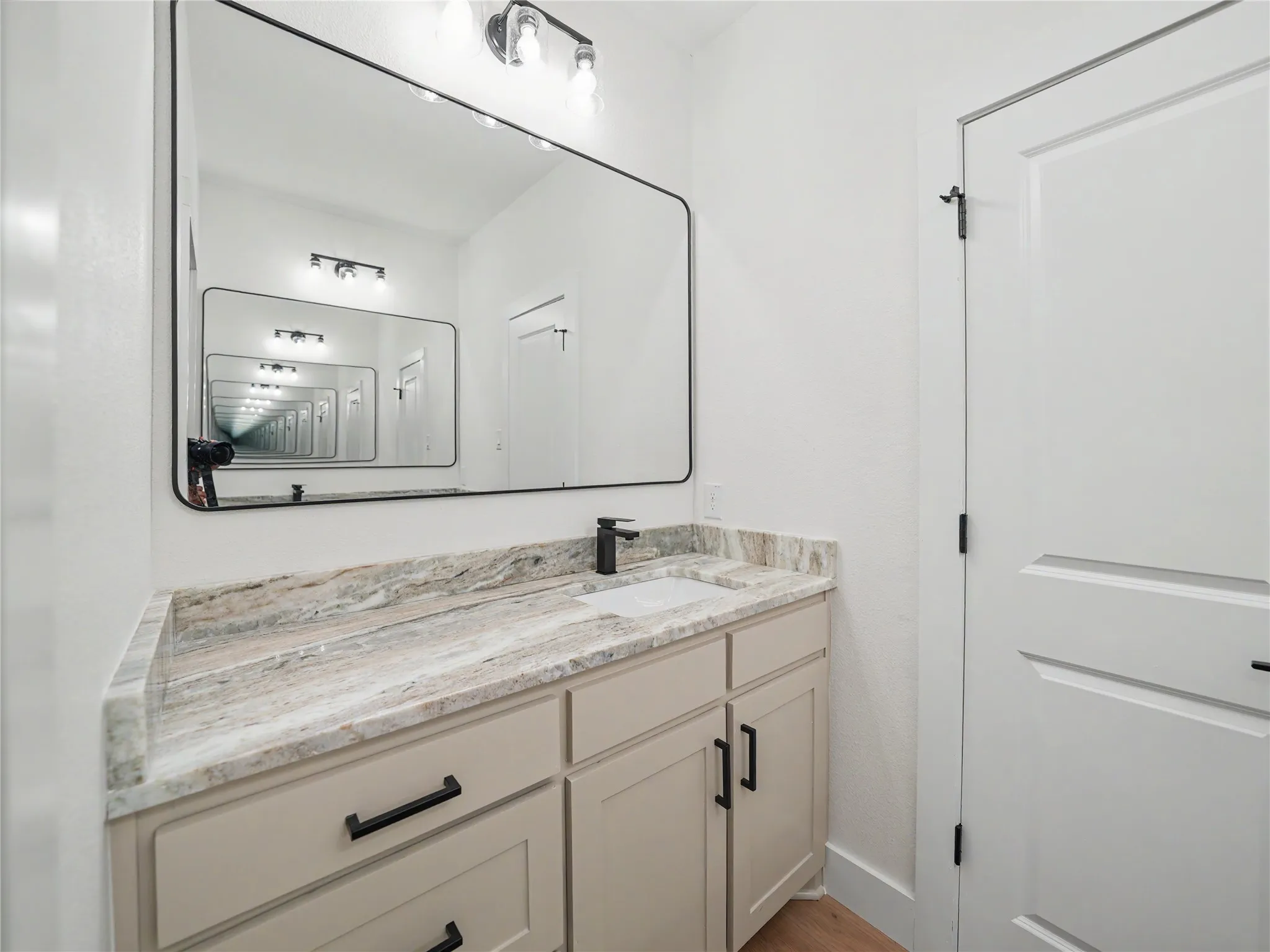 Bathroom vanity featuring an integrated sink, stone-finish countertop, and matte black fixtures
