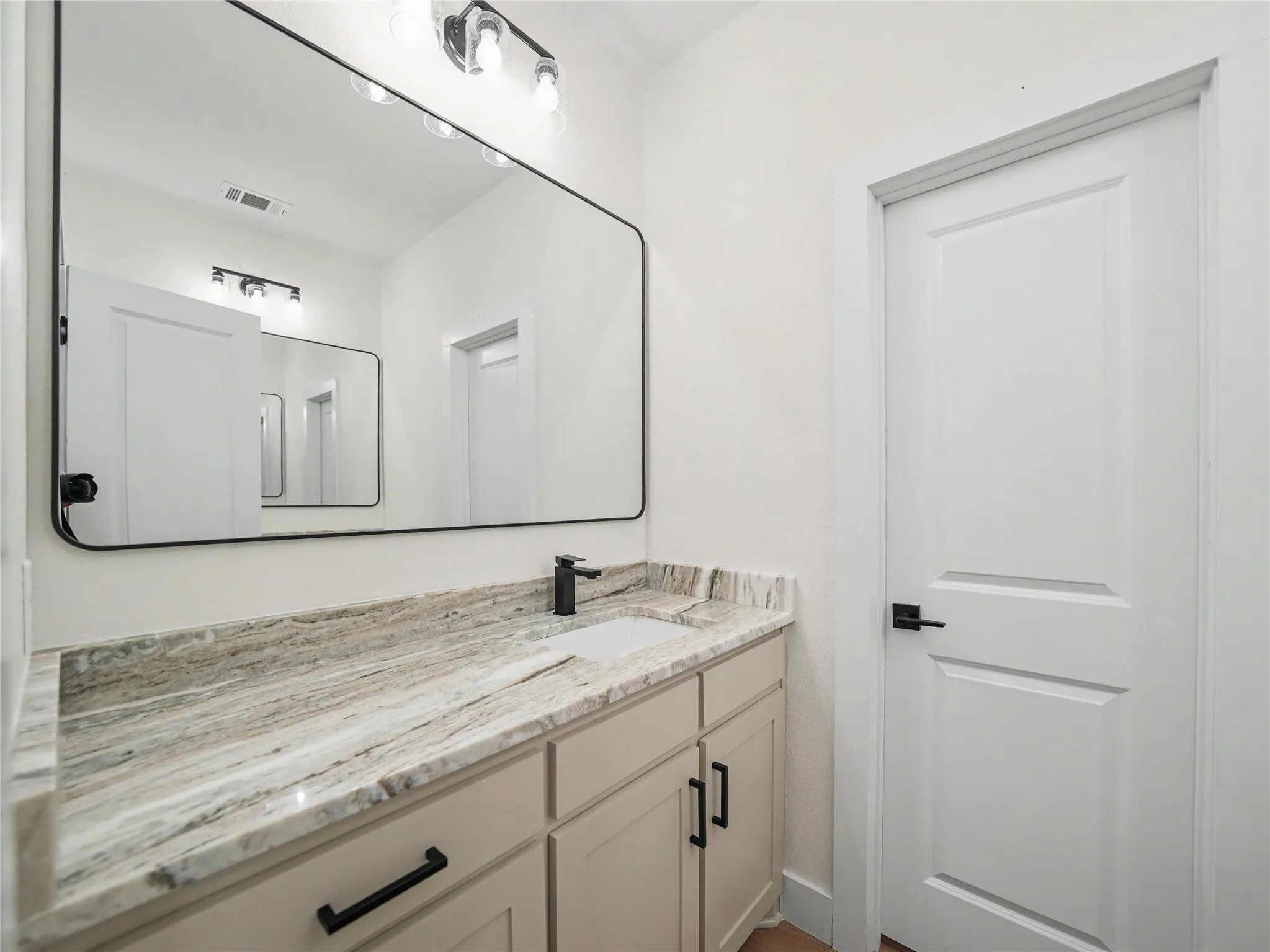 Bathroom vanity featuring a light-toned countertop, an undermount sink, and matte black fixtures