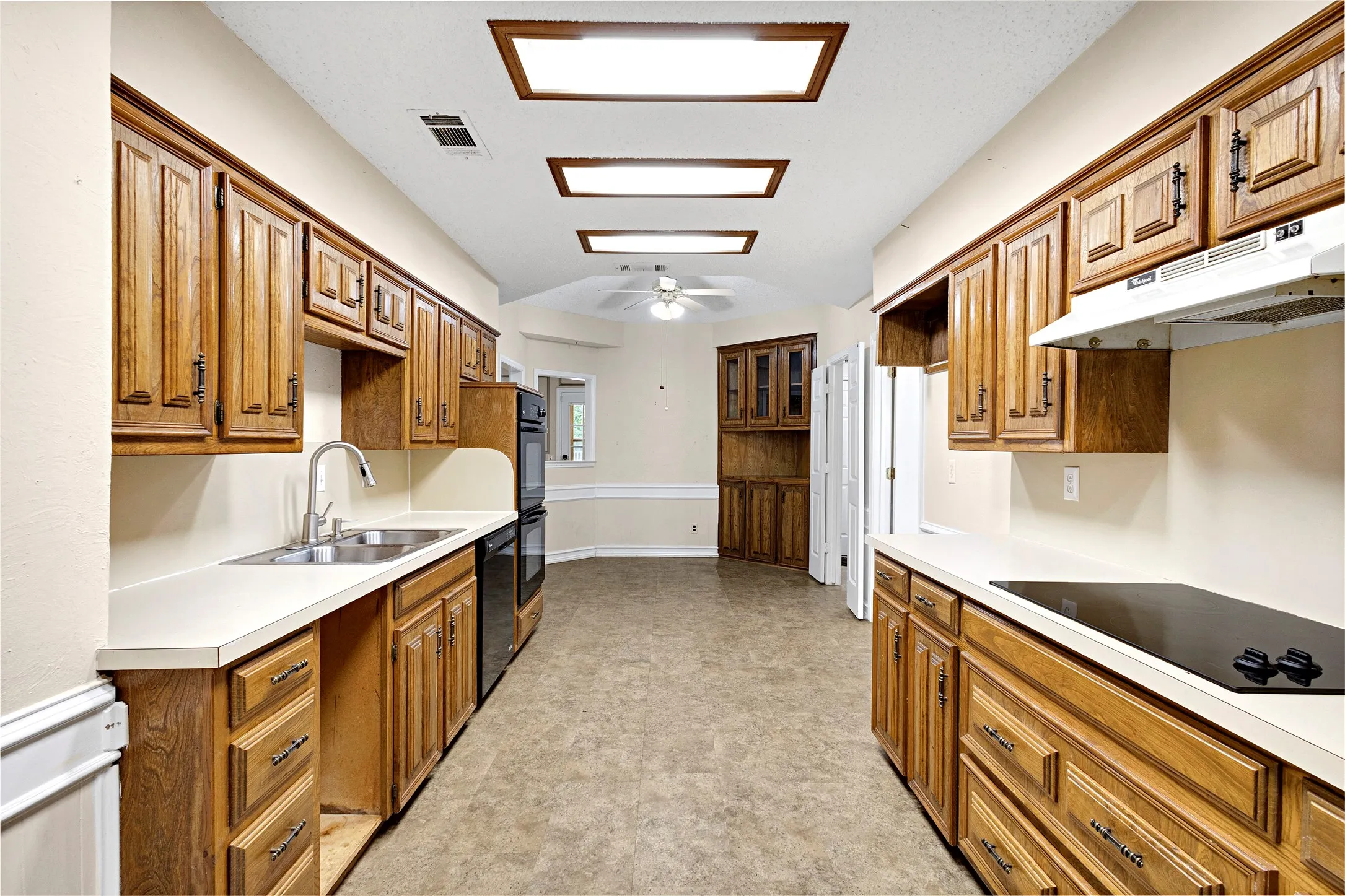 Kitchen featuring extensive cabinetry, white countertops, built-in double ovens, and a smooth-top electric cooktop