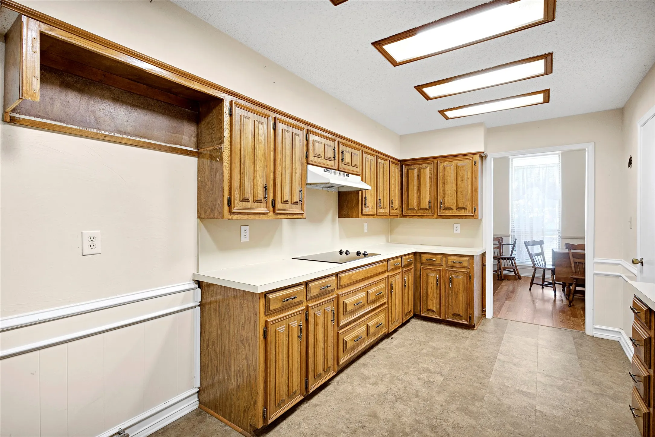 Full kitchen featuring extensive wood cabinetry, light-toned countertops, and a built-in cooktop