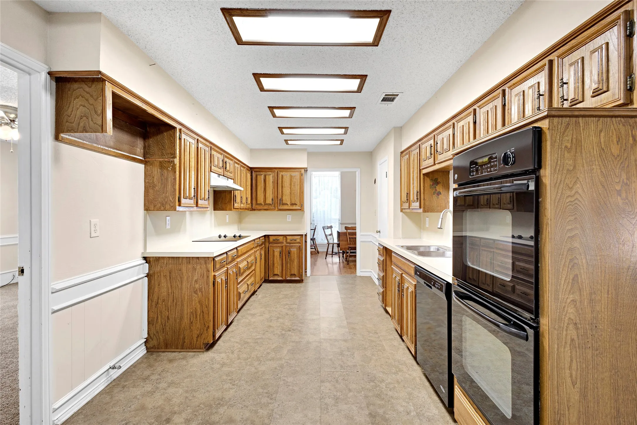 Kitchen featuring extensive wood cabinetry, light countertops, and integrated double wall ovens