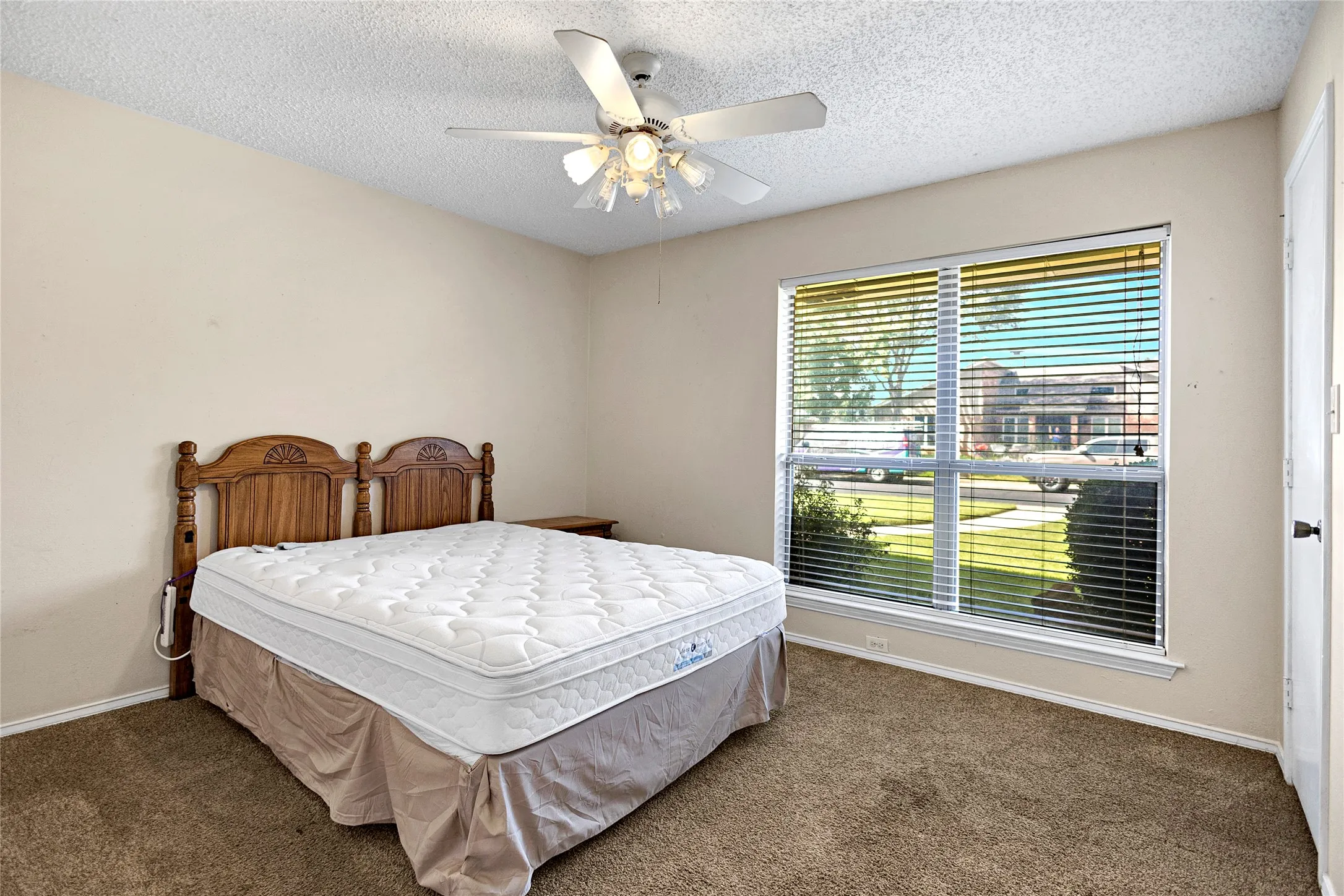 Carpeted room with a large window featuring horizontal blinds