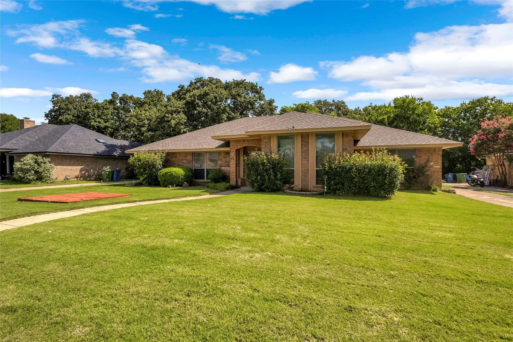 Traditional brick exterior featuring a hip roof and established front landscaping