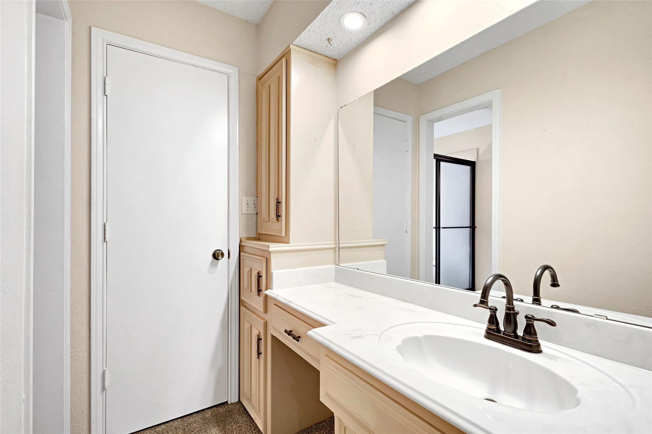 Bathroom vanity featuring an integrated sink, broad mirror, and built-in cabinetry with a dedicated dressing area