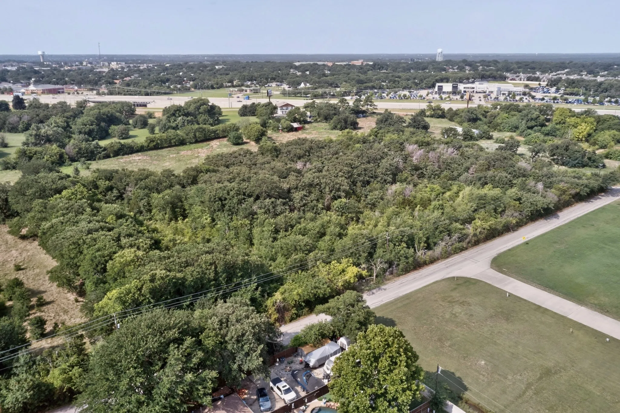 Expansive wooded lot featuring a paved road frontage and scattered mature trees