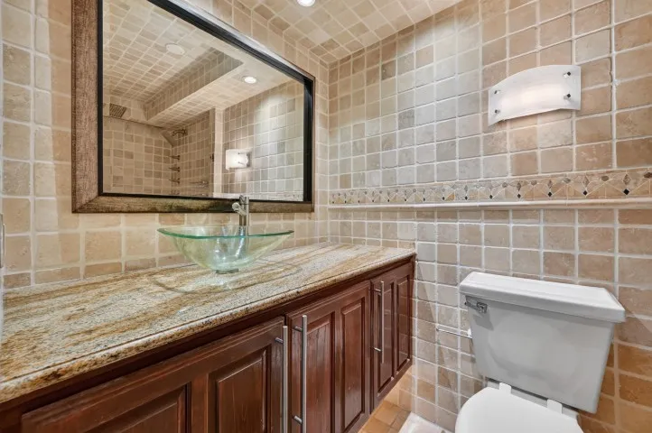 Bathroom vanity with a vessel sink, stone countertop, and wood cabinetry