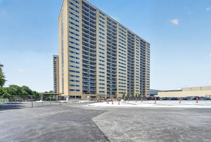 High-rise residential building featuring multiple balconies and a beige facade