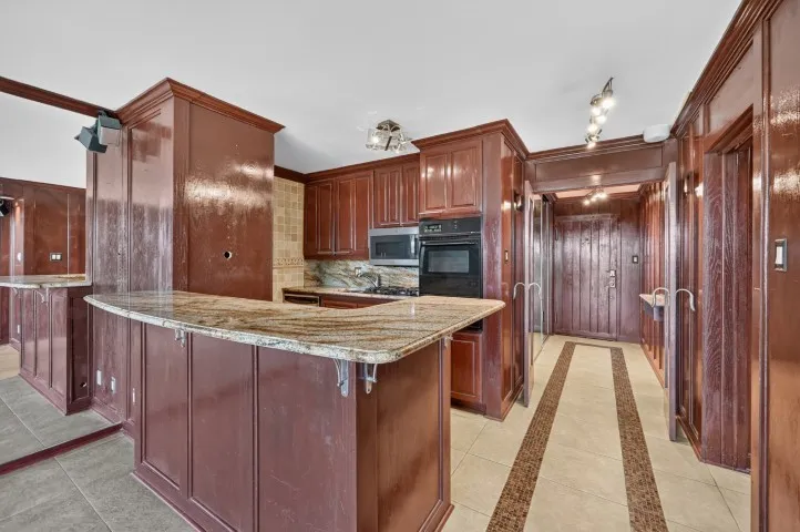 Kitchen area featuring wood-finish cabinetry, granite countertops, and stainless steel appliances