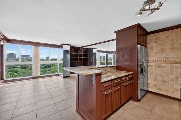 Open-concept living area with extensive window coverage, tile flooring, and integrated kitchen features