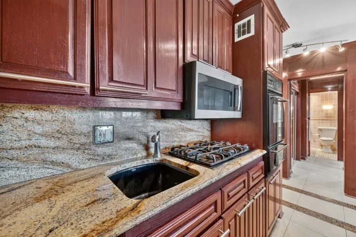 Kitchen featuring rich wood cabinetry, stone-finish countertops, and a built-in gas cooktop