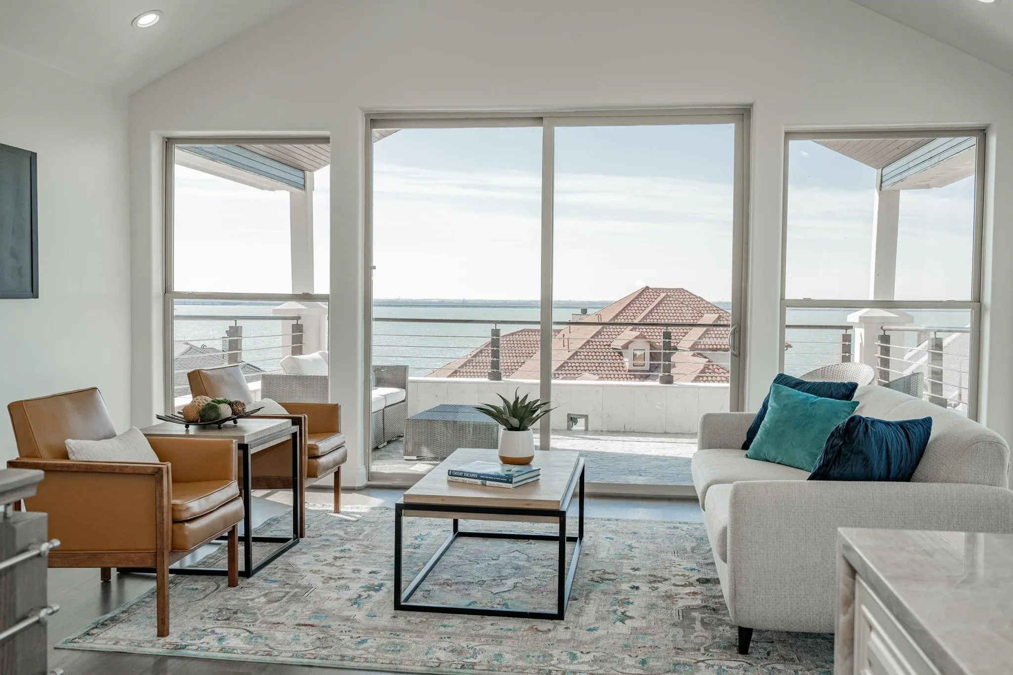 Vaulted ceiling living area featuring a full-width sliding glass door, recessed lighting, and expansive water scenery