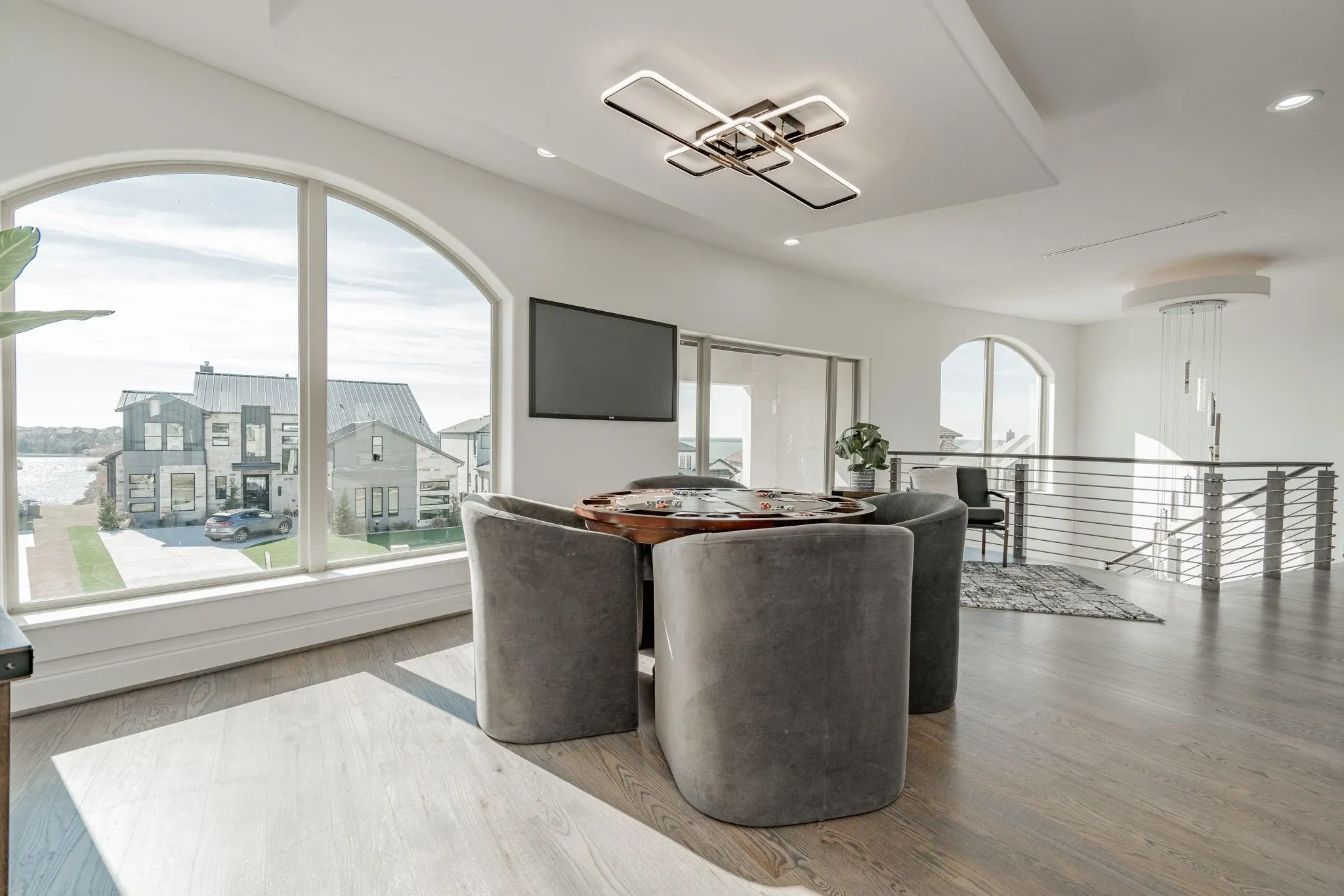 Upper-level space featuring a large arched window, wood-finish flooring, and a contemporary ceiling light fixture