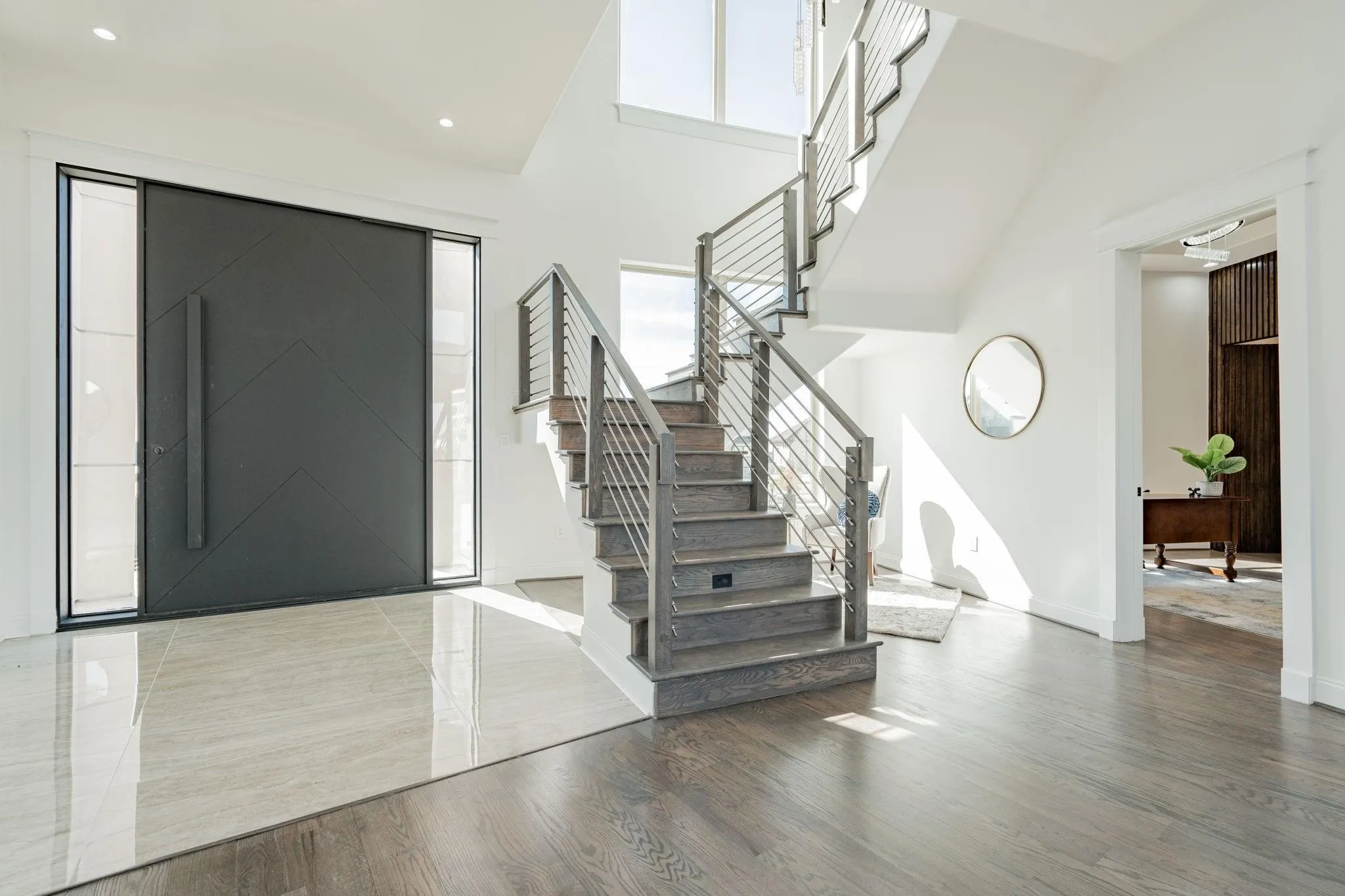 Foyer with a contemporary dark entry door, glass sidelights, and a two-story ceiling