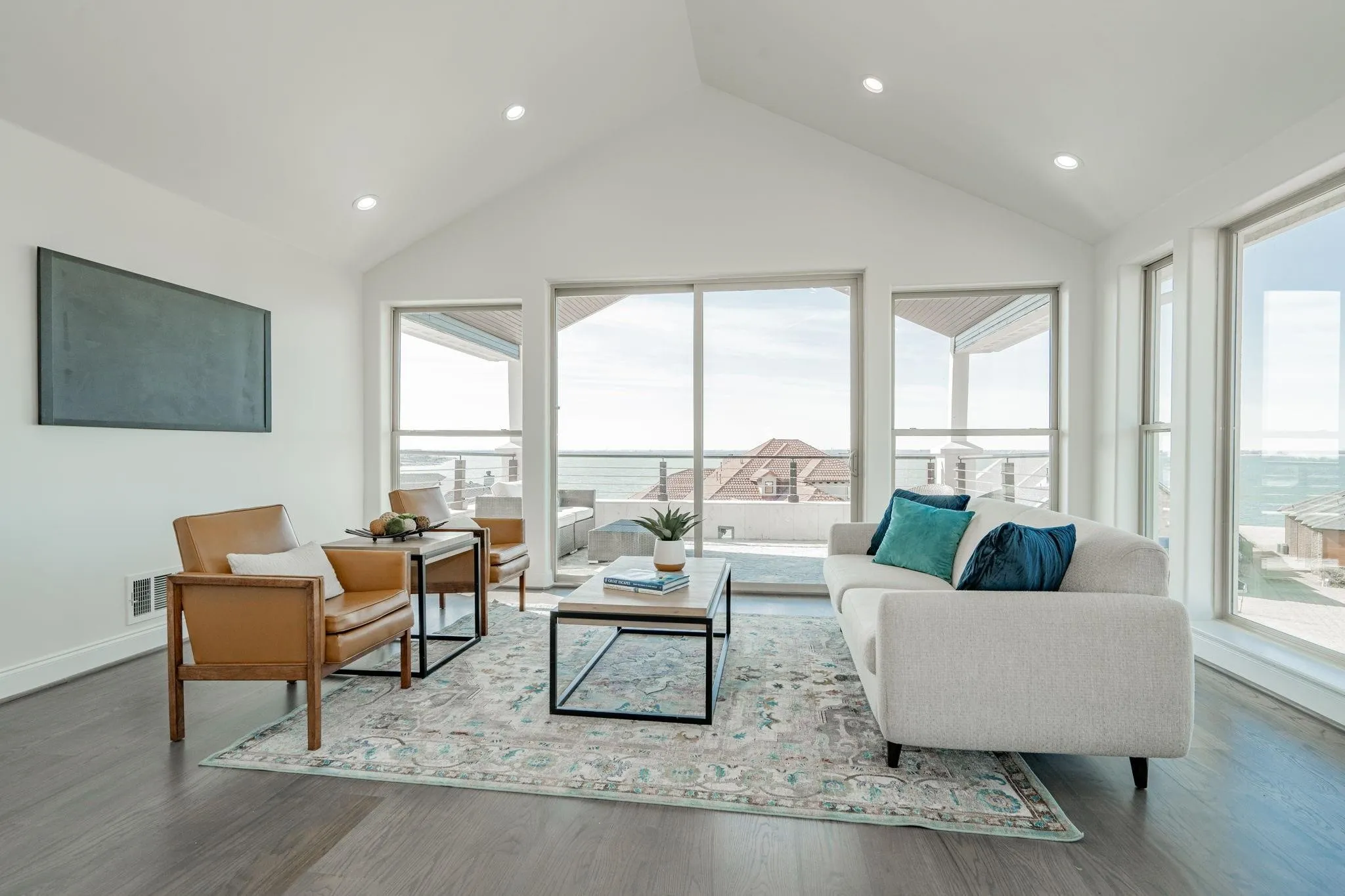 Vaulted ceilings accentuate this open living area featuring wood-finish flooring, recessed lighting, and expansive windows providing abundant light