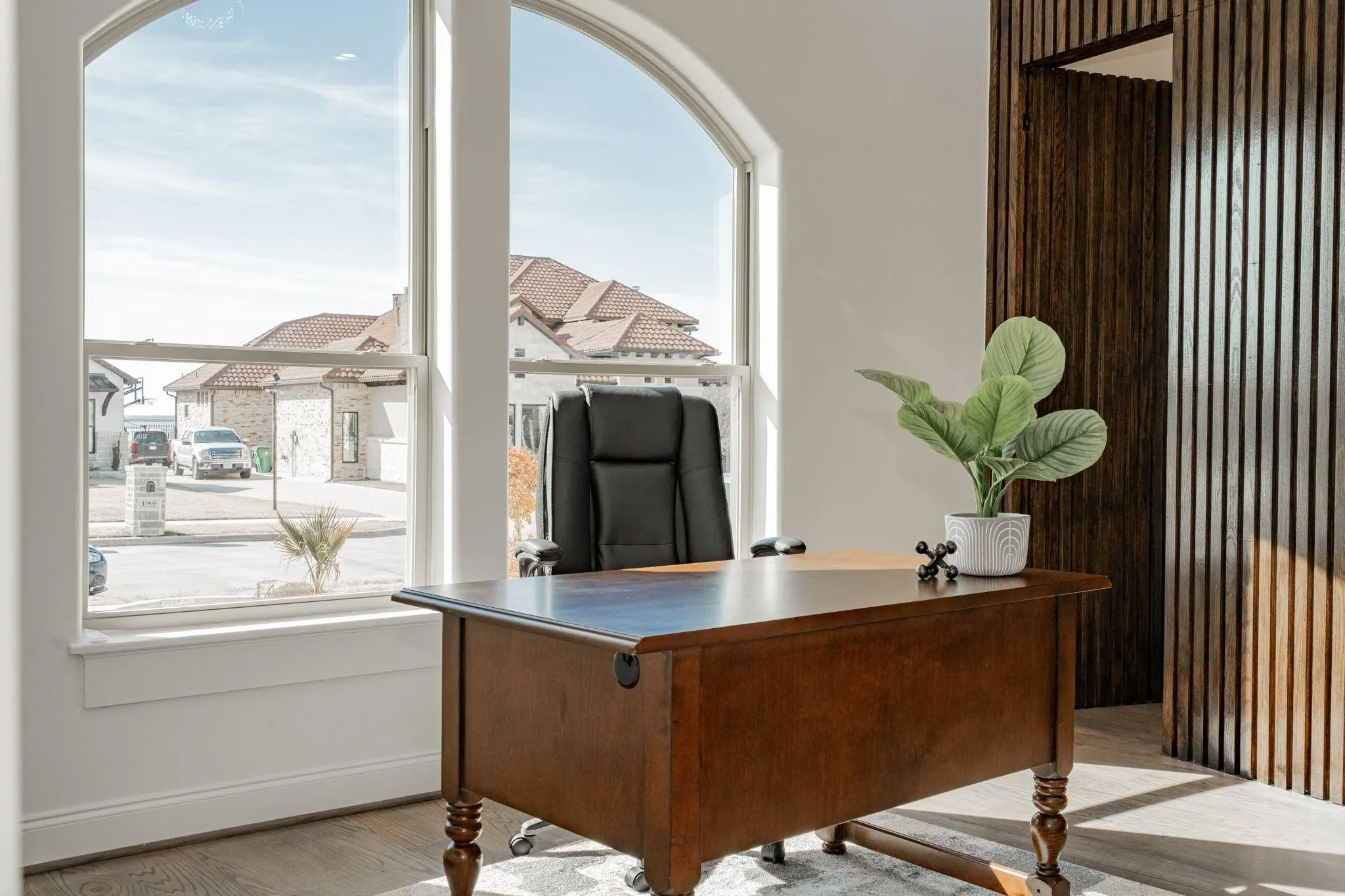 Arched window framing a bright interior space with wood-finish flooring