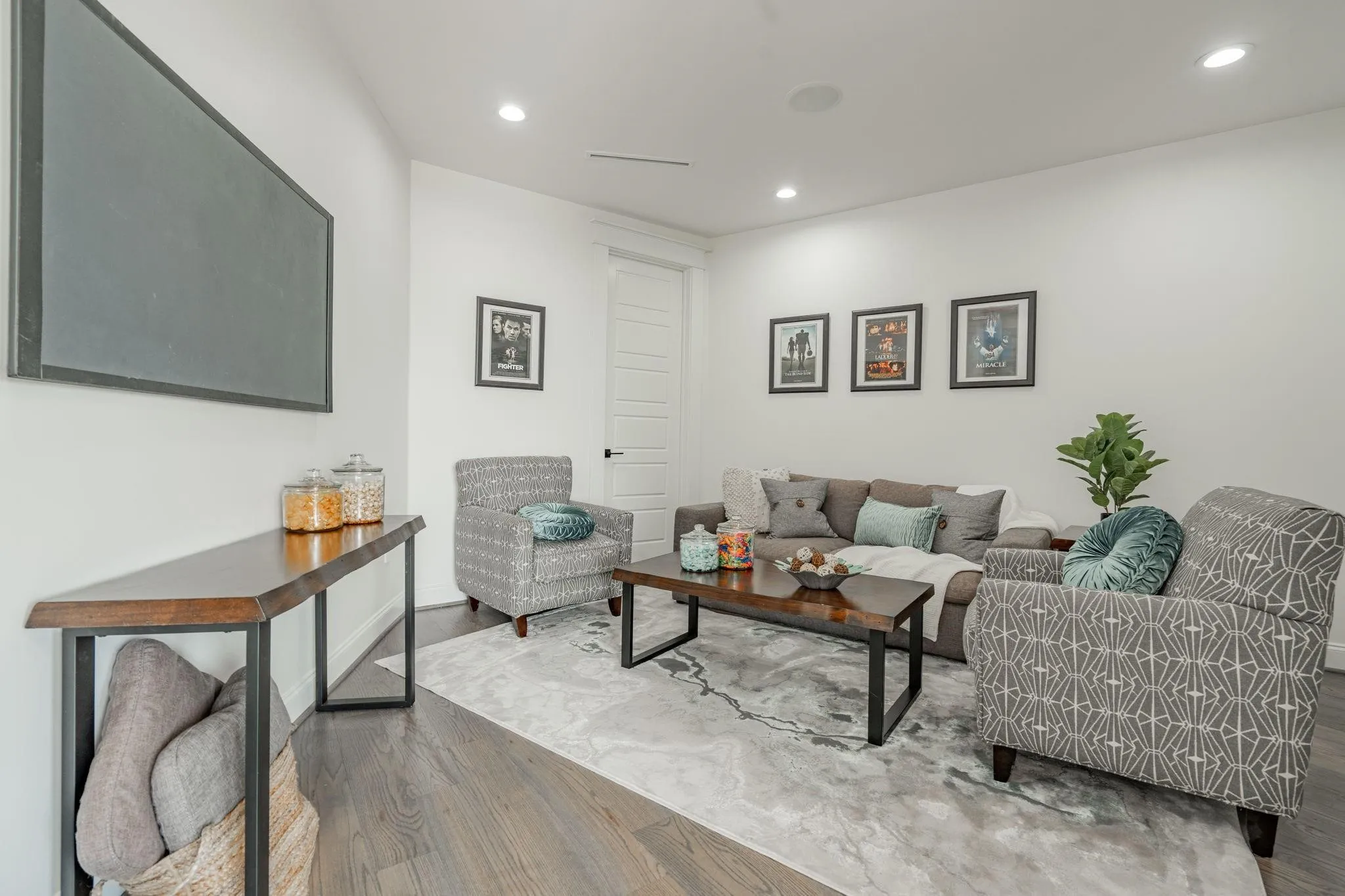Spacious living area featuring wood-finish flooring, recessed lighting, and a modern console table