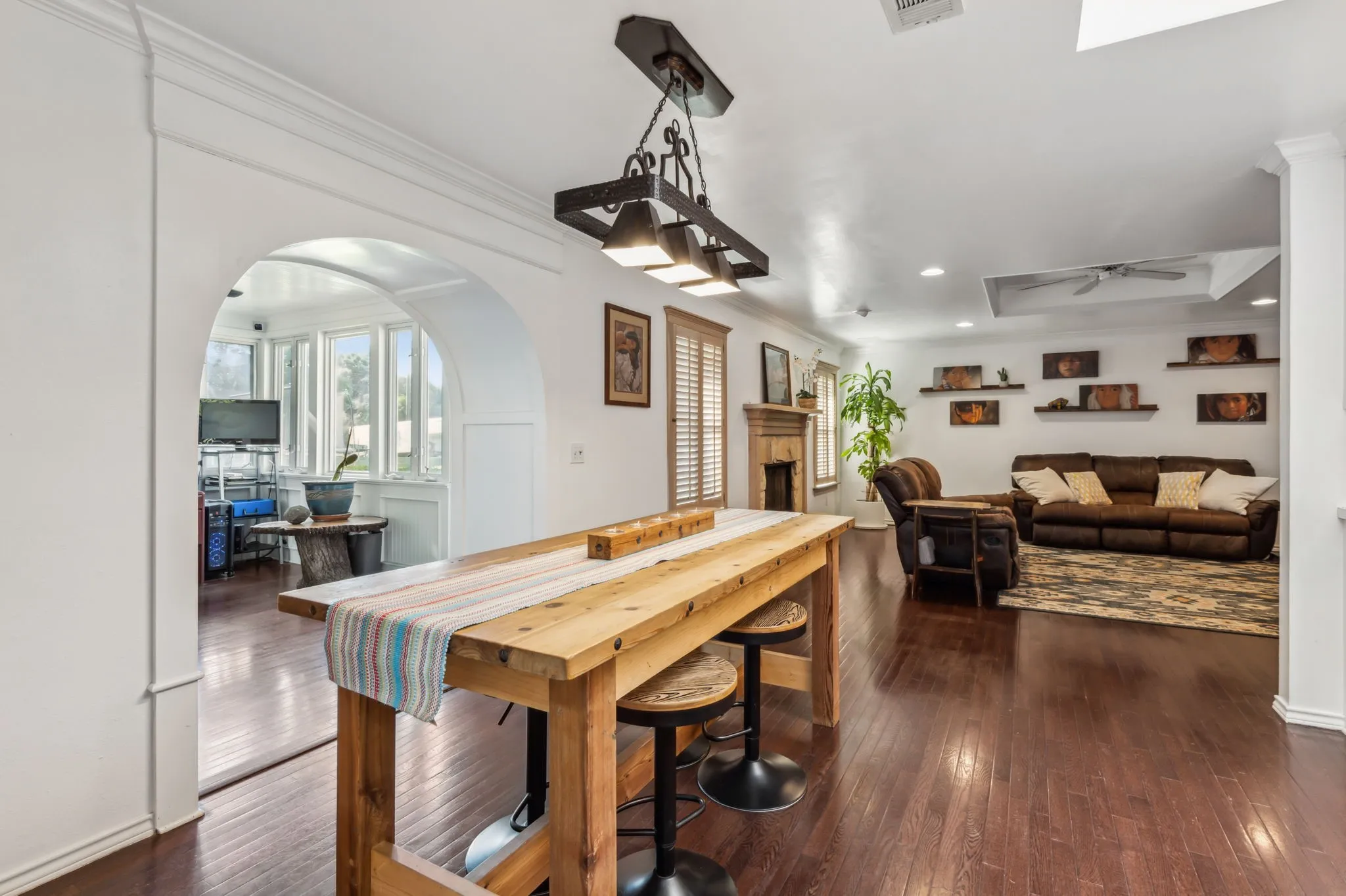 Open-concept living area featuring rich wood-finish flooring, a decorative fireplace with wood mantel, and an arched entryway