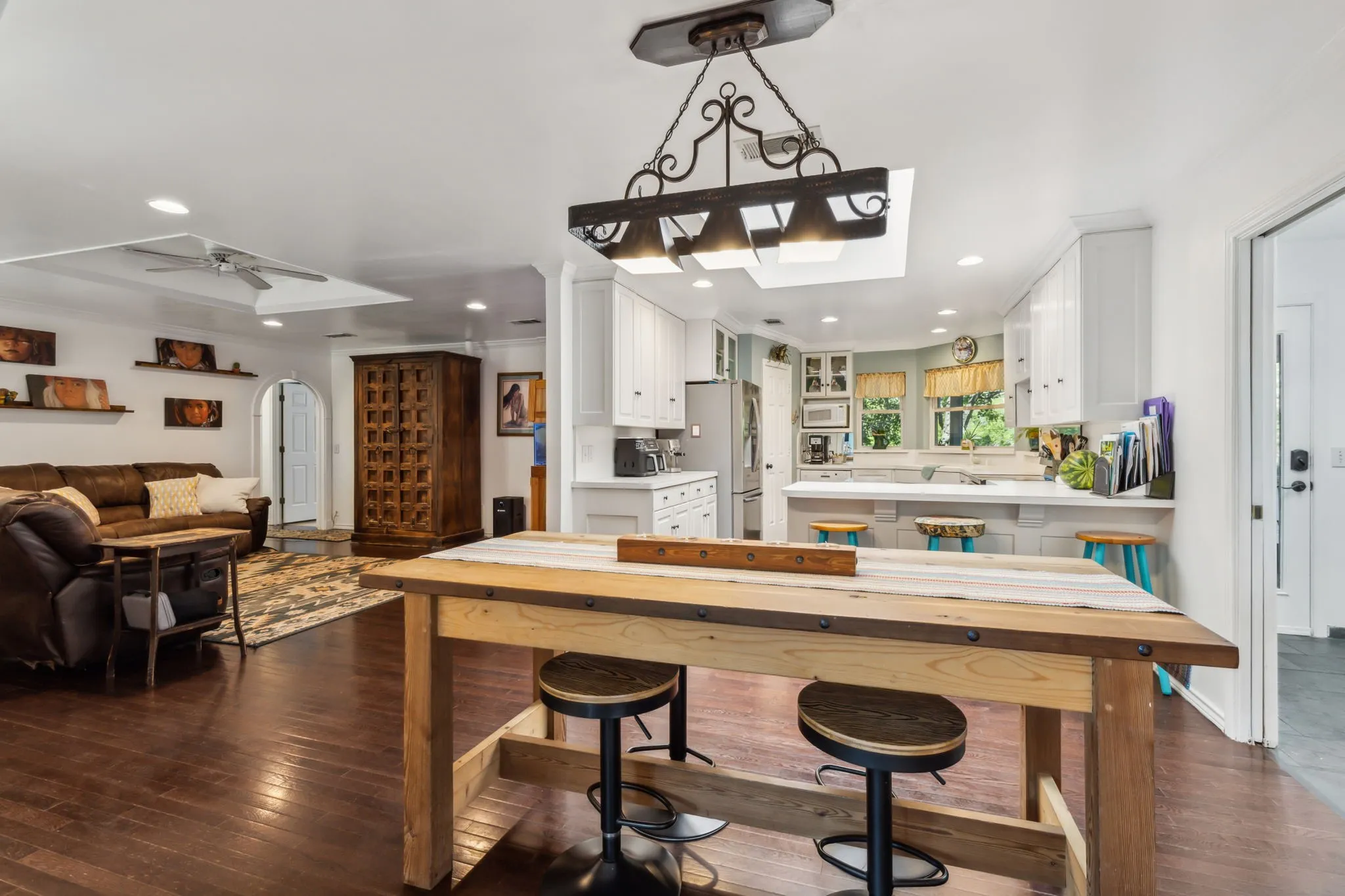 Open-concept kitchen and living area featuring dark wood-finish flooring, a kitchen island with seating, white cabinetry, and recessed lighting