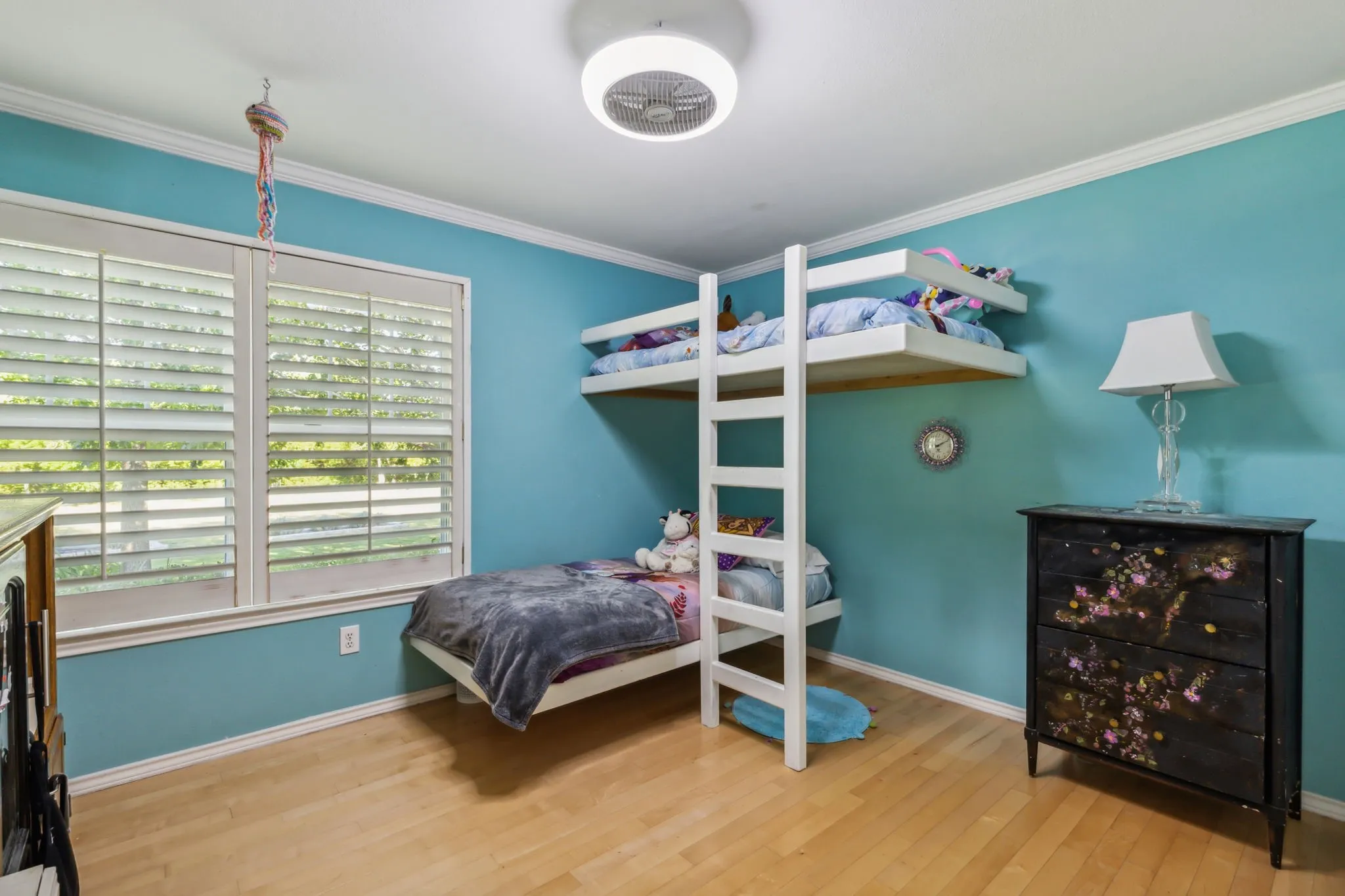 Bright room featuring light wood-finish flooring, white crown molding, and a ceiling-mounted light fixture