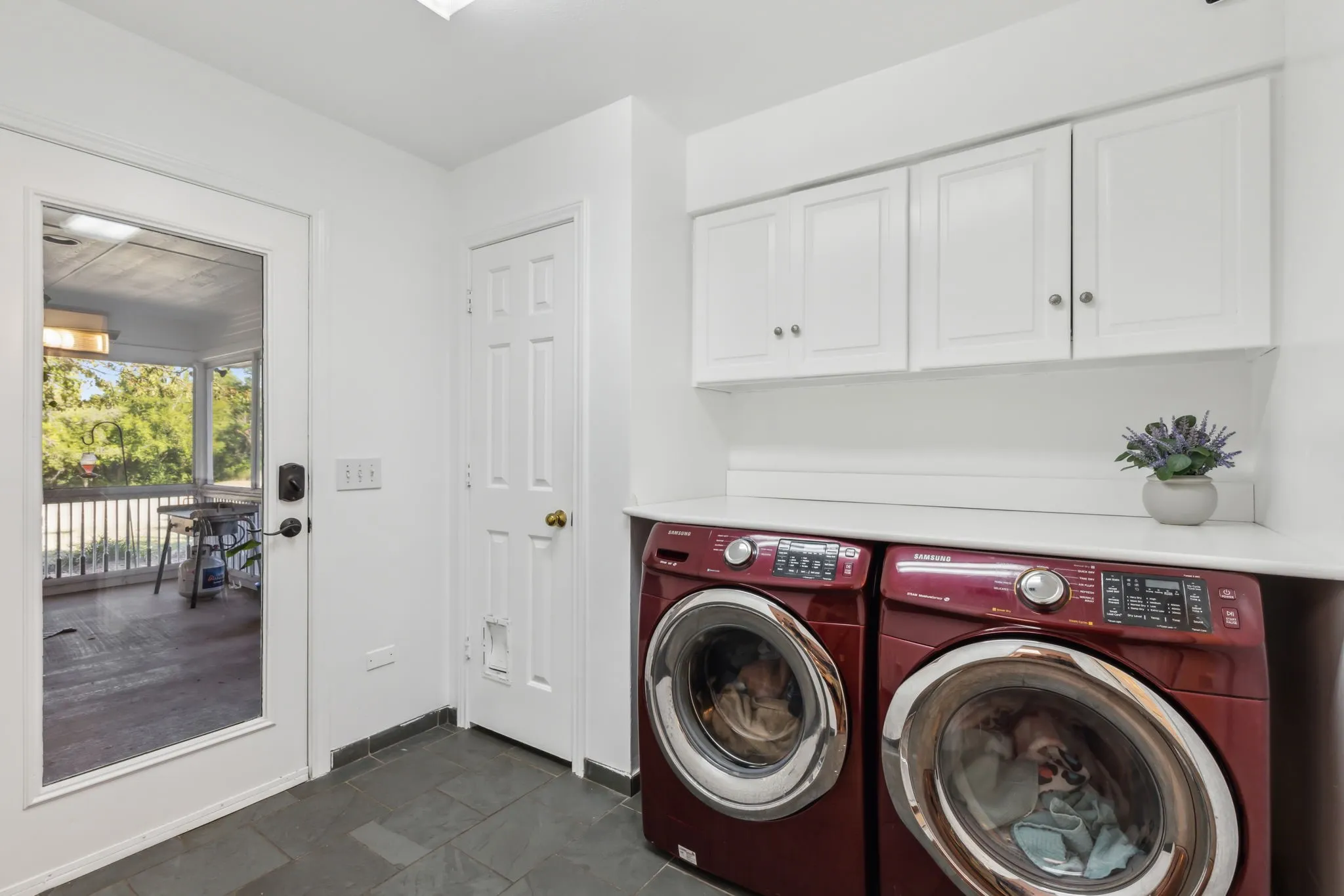 Laundry area featuring slate tile flooring, white shaker-style cabinetry, and a light-toned countertop