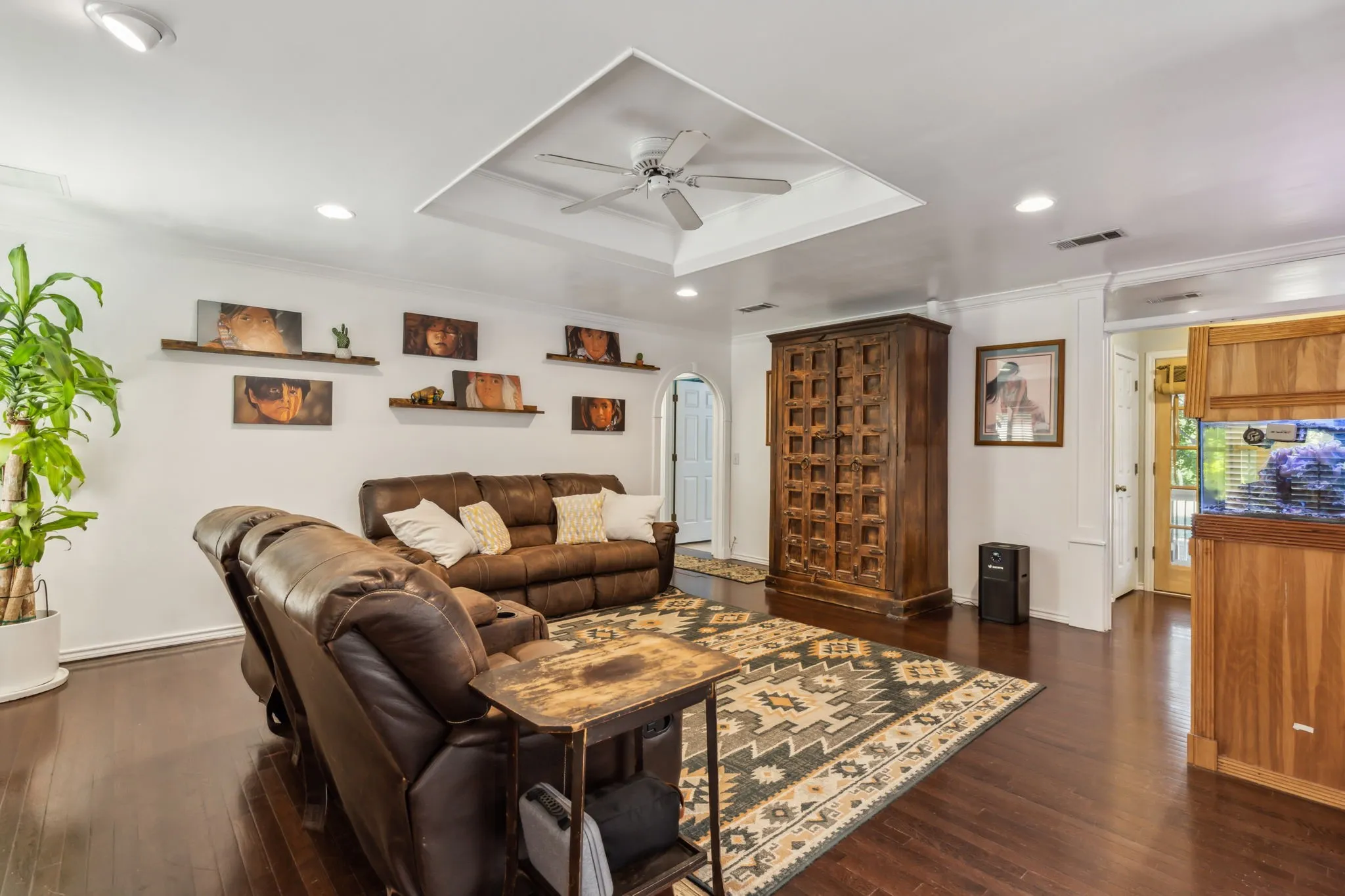 Living area featuring dark wood-finish flooring, recessed lighting, and a tray ceiling with a ceiling fan