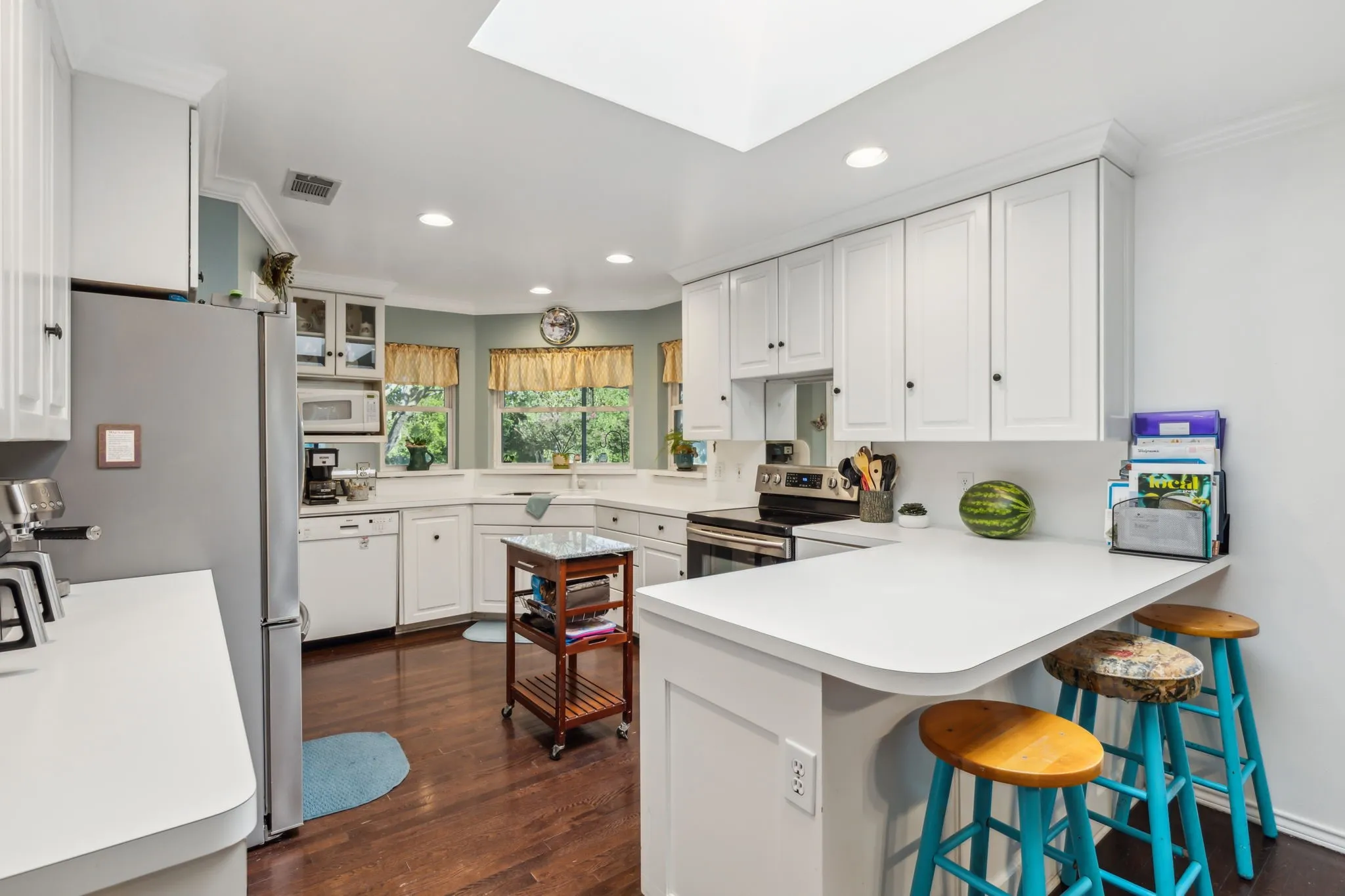 Kitchen featuring white cabinetry, a skylight, recessed lighting, wood-finish flooring, and a breakfast bar