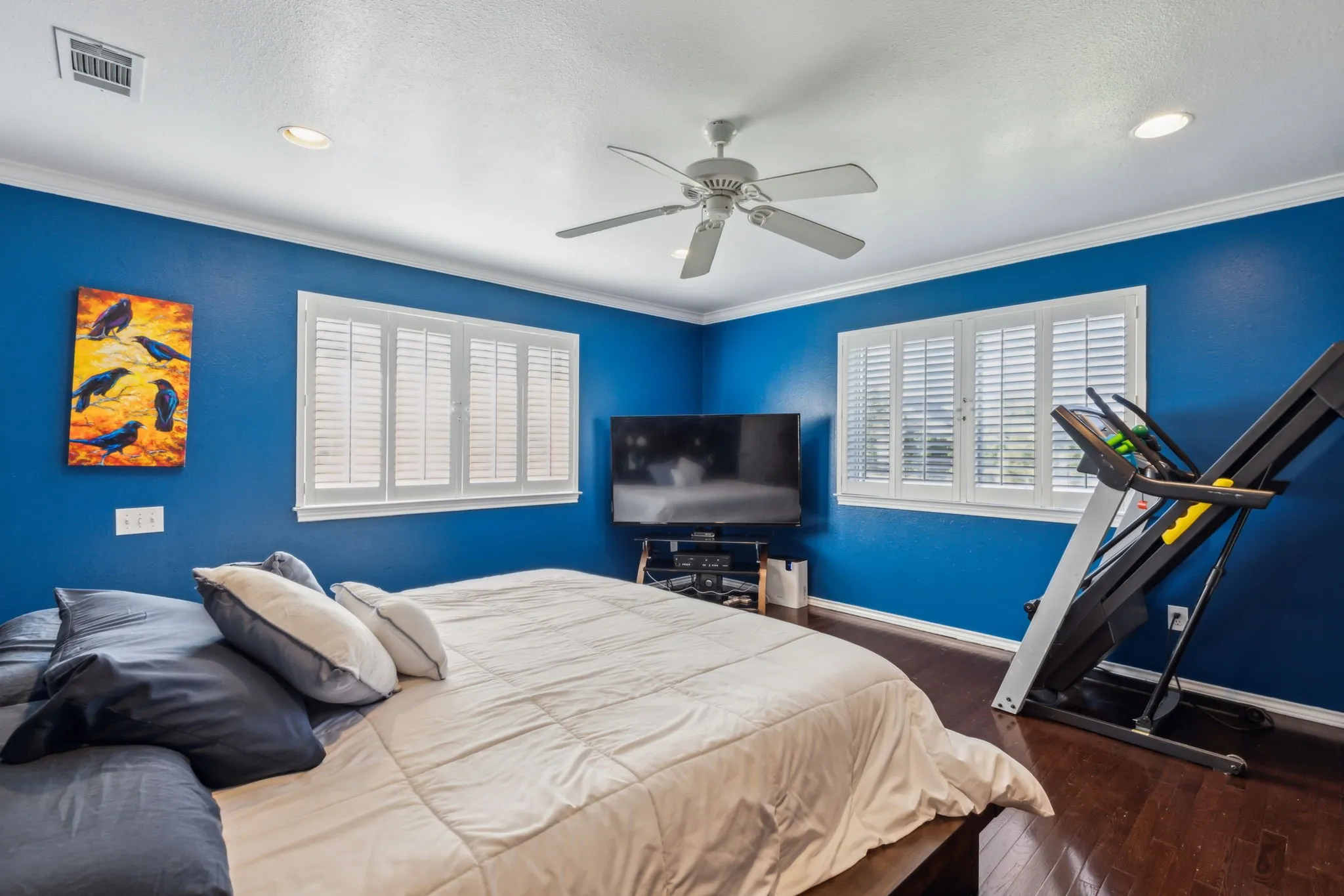 Room featuring two windows with white plantation shutters, rich wood-finish flooring, a ceiling fan with integrated lighting, and recessed lighting