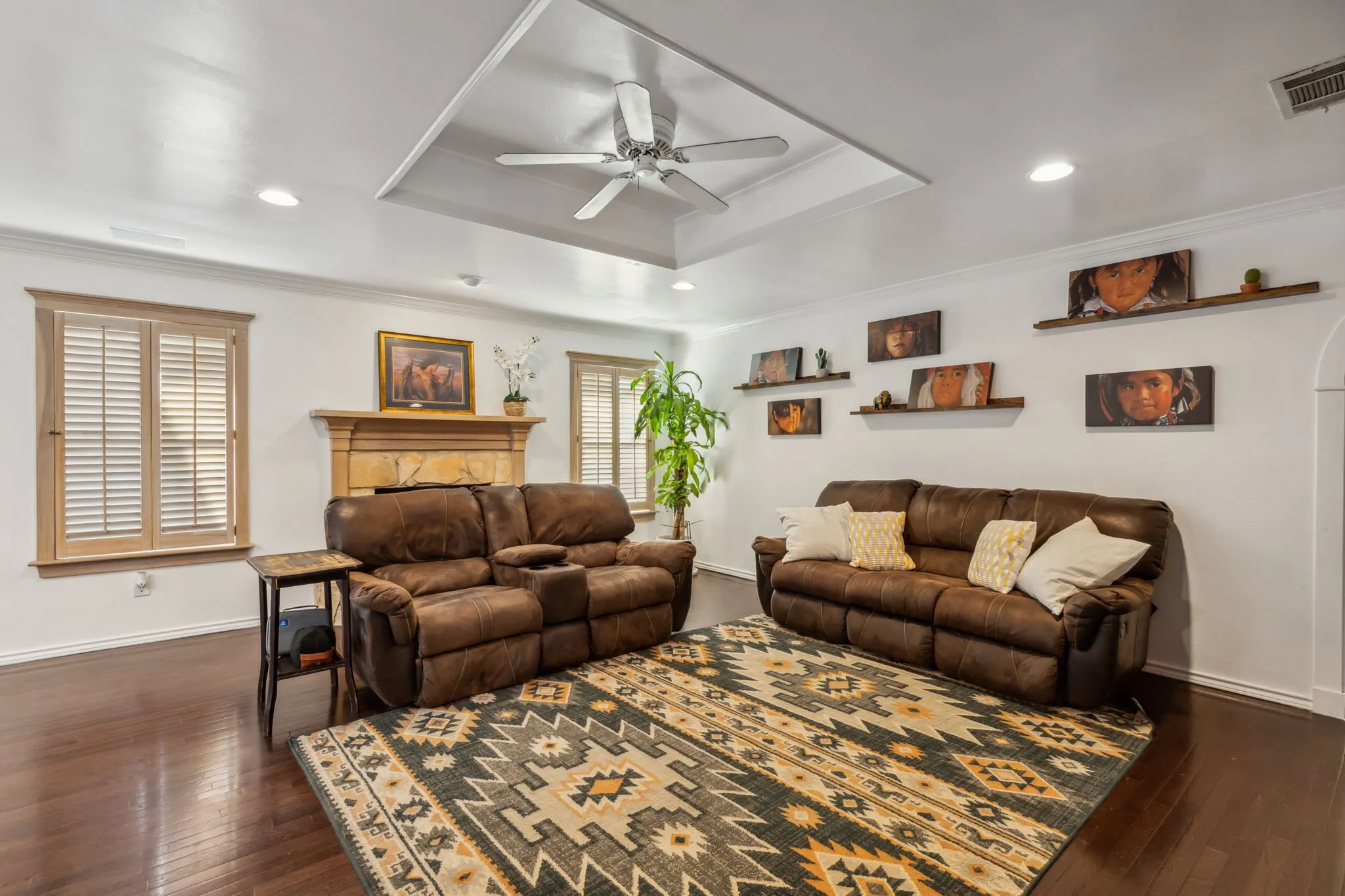 Spacious living area featuring dark wood-finish flooring and a tray ceiling with a ceiling fan