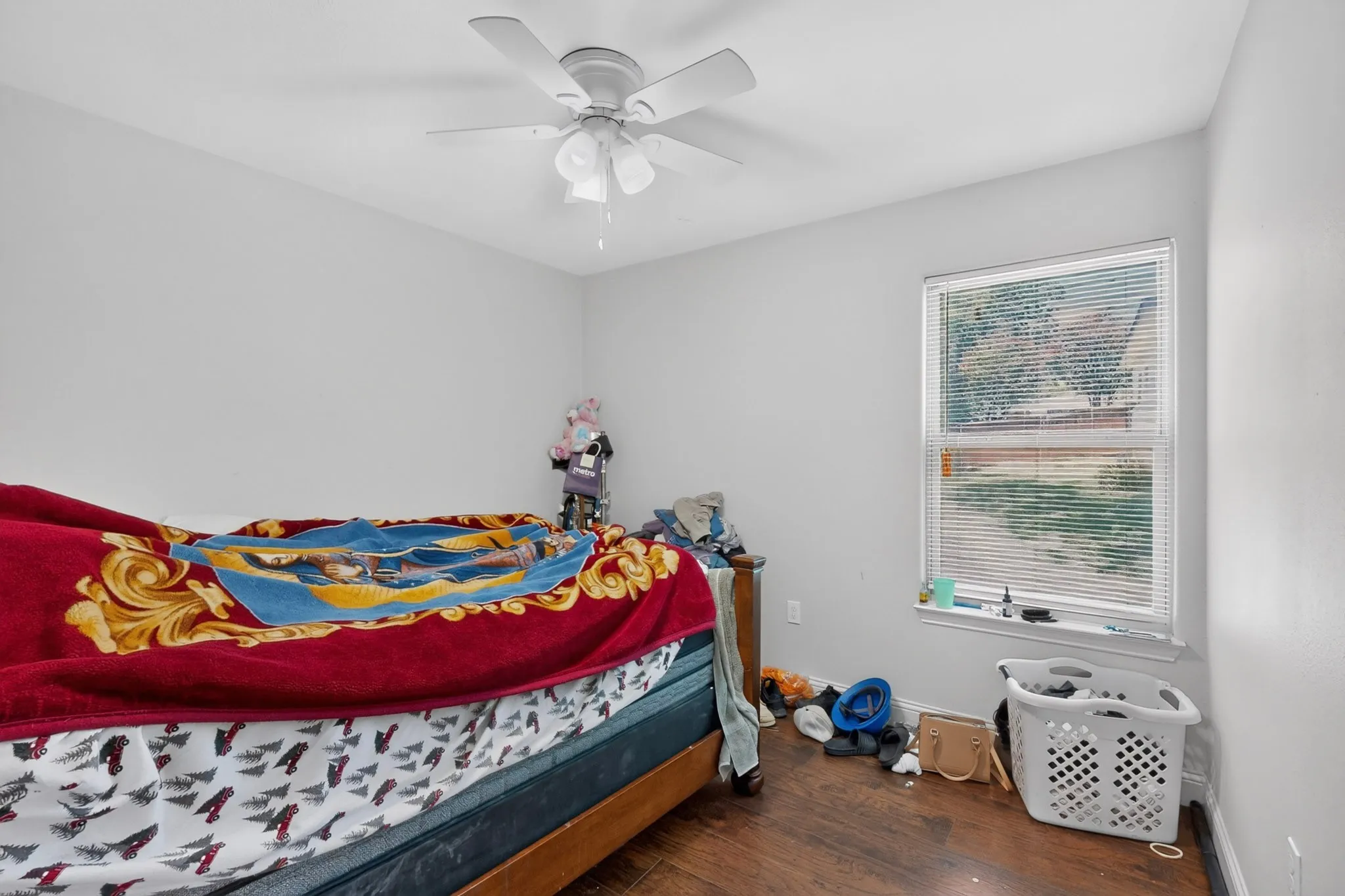 Bedroom featuring a ceiling fan with integrated lighting, wood-finish flooring, and a window with blinds