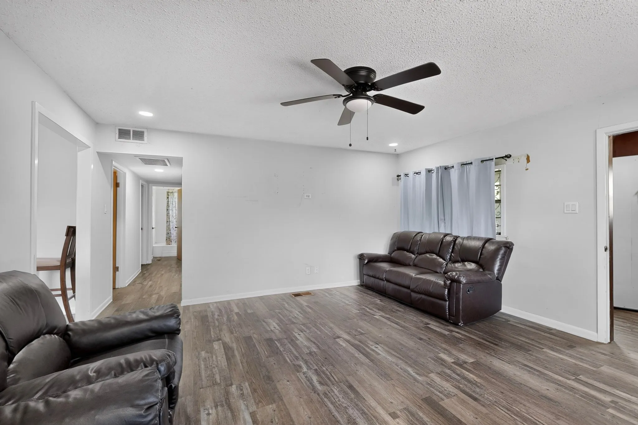 Spacious living area featuring wood-finish flooring, recessed lighting, and a ceiling fan with integrated light
