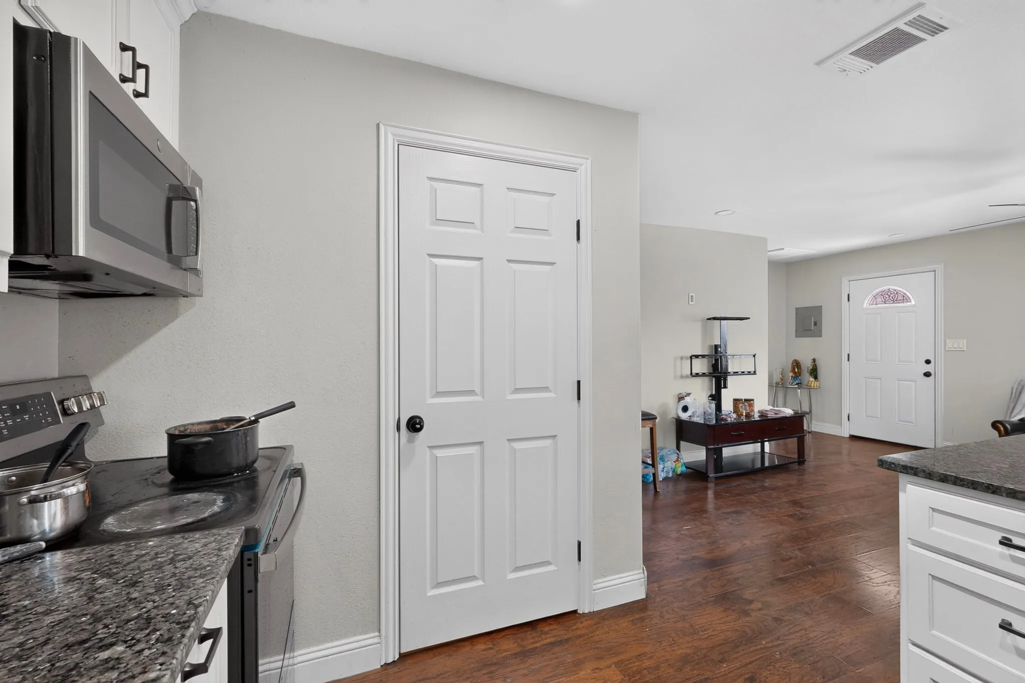 Kitchen featuring granite-style countertops, stainless steel microwave, and white cabinetry
