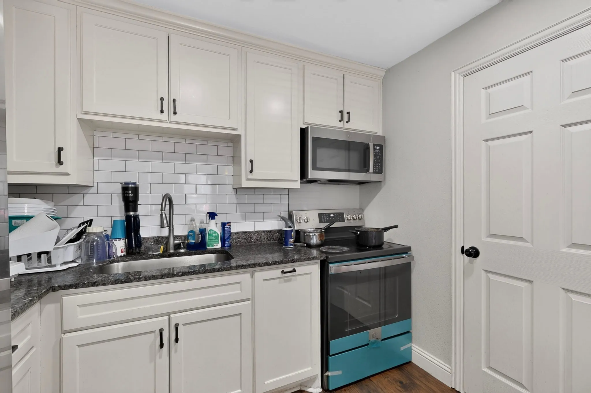 Kitchen featuring white shaker-style cabinetry, dark speckled countertops, and a subway tile backsplash