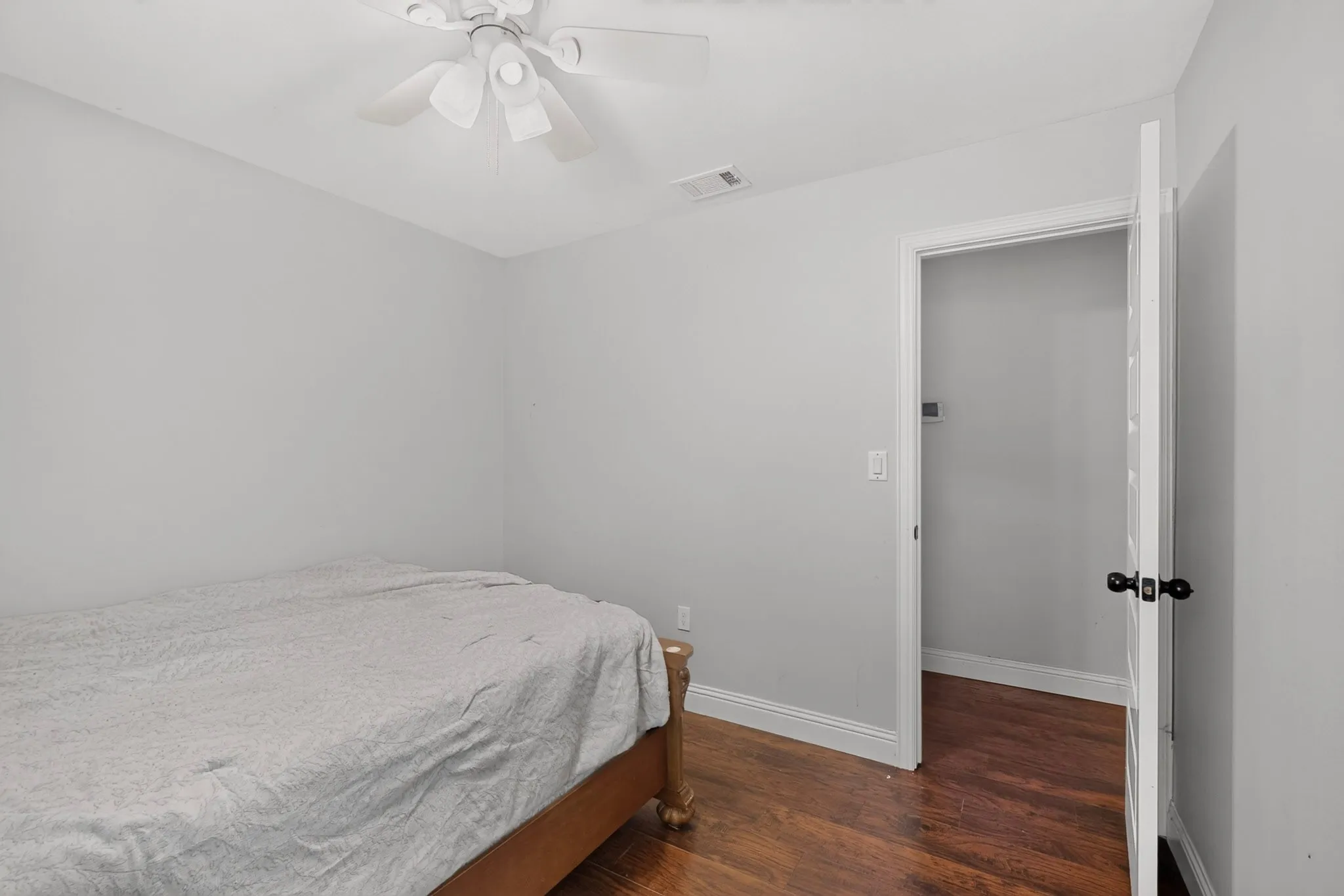 Light-filled interior space featuring wood-finish flooring, a white ceiling fan, and crisp white trim