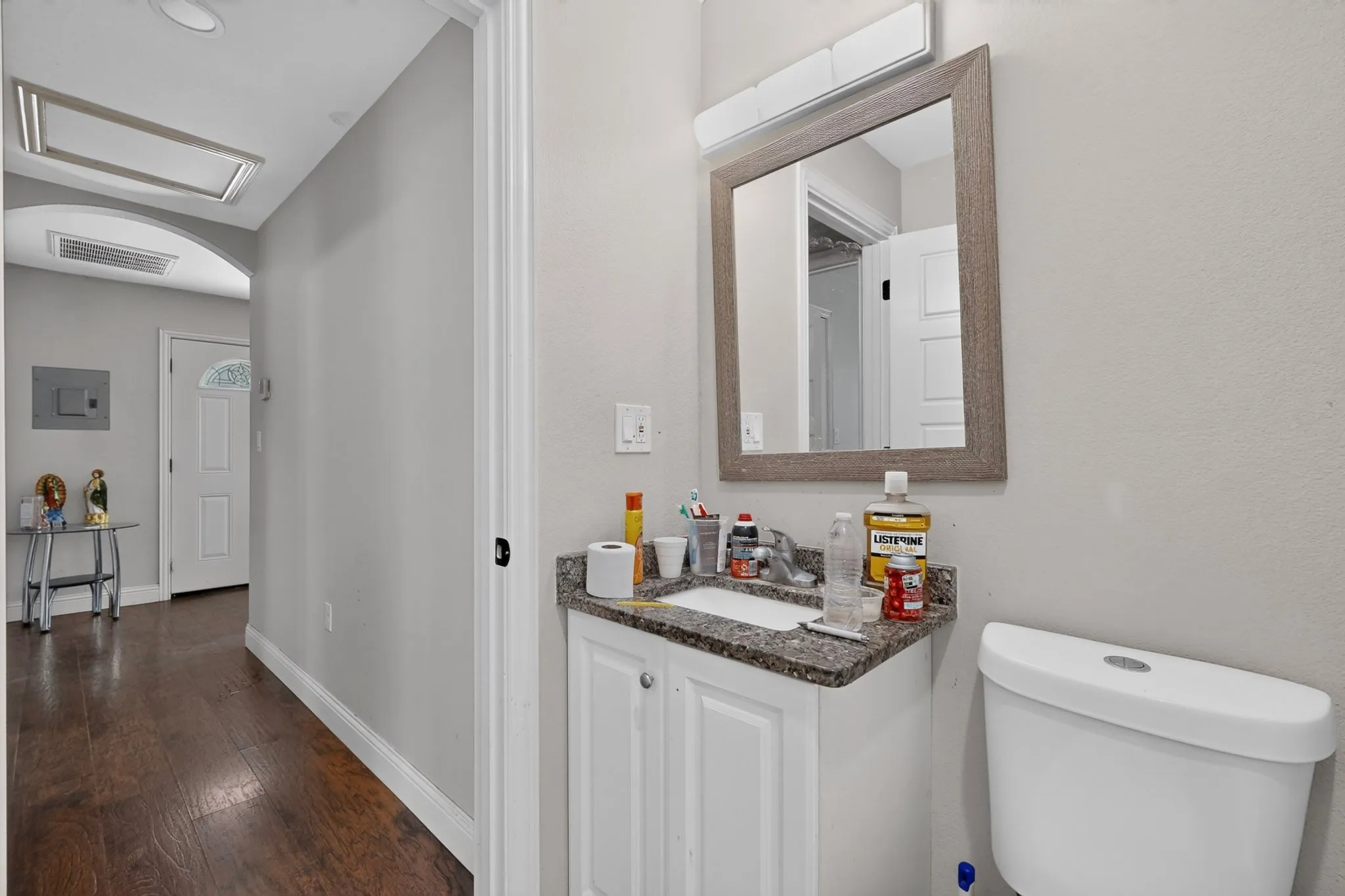 Bathroom featuring a white vanity with a granite-style countertop, undermount sink, and framed mirror