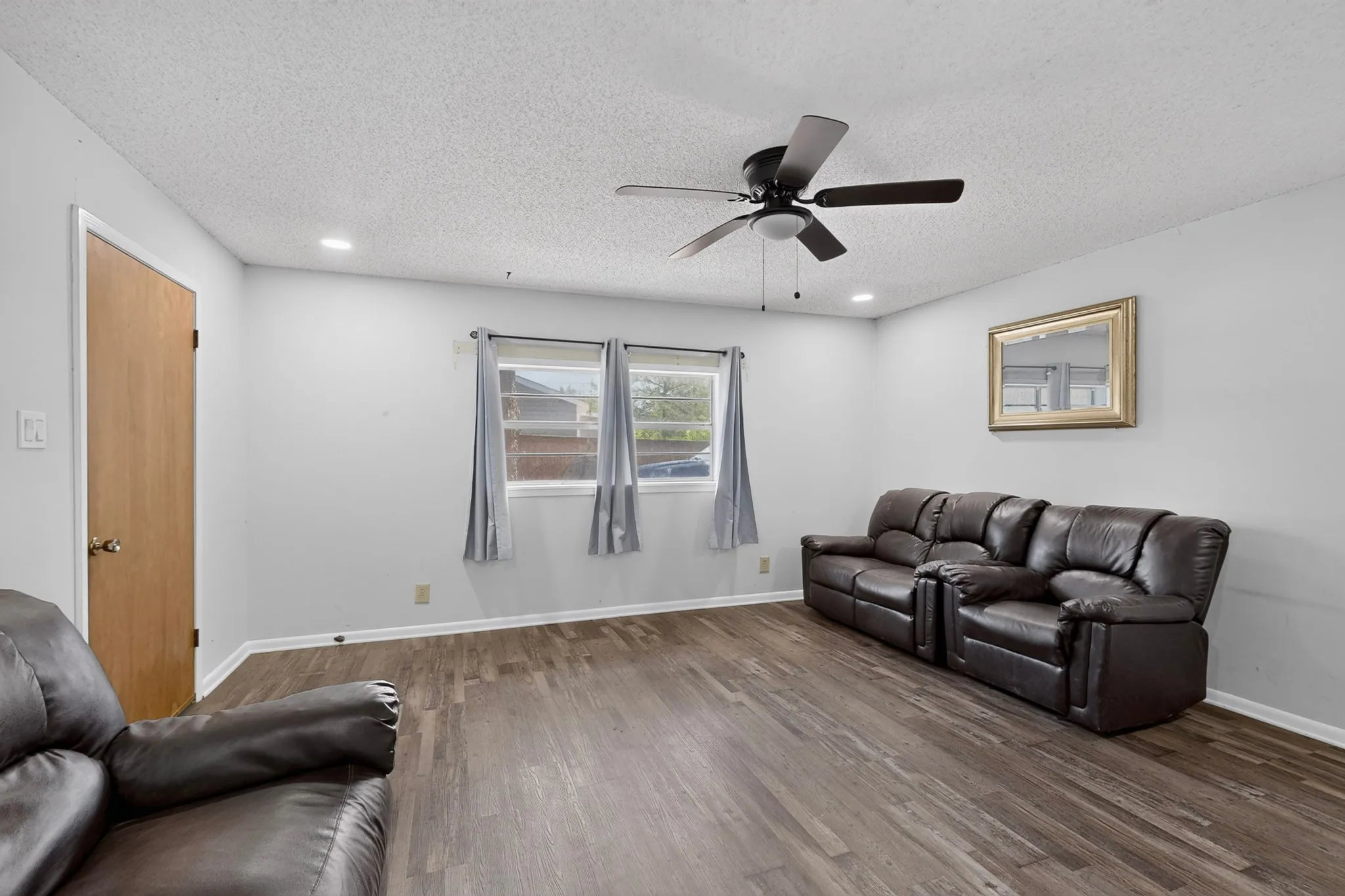 Spacious interior featuring wood-finish flooring, light grey wall paint, and multiple windows