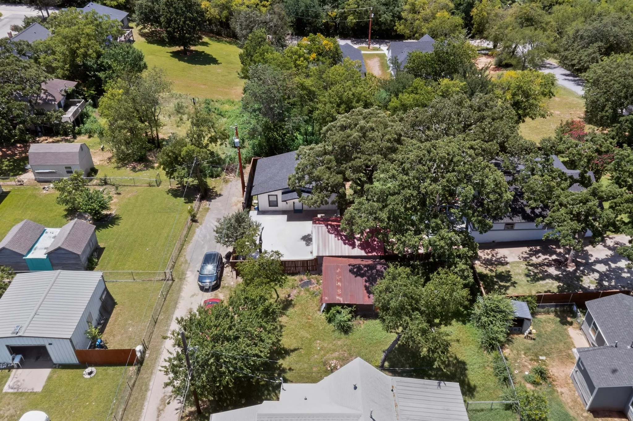 Expansive property featuring a mix of mature trees, open green spaces, and partial fencing