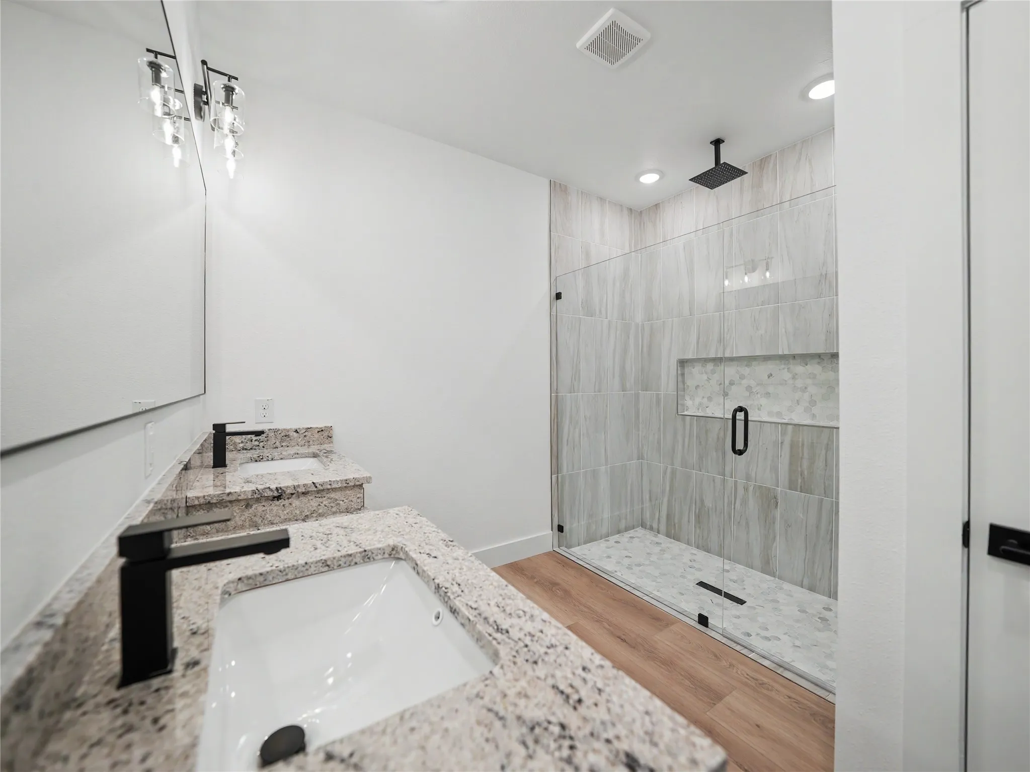 Spacious bathroom featuring a dual vanity with granite countertops, undermount sinks, and matte black fixtures