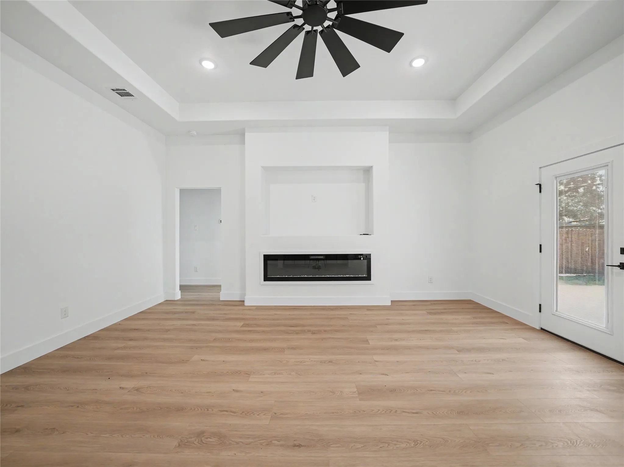 Spacious interior with wood-finish flooring, a built-in electric fireplace, recessed lighting, and a contemporary ceiling fan