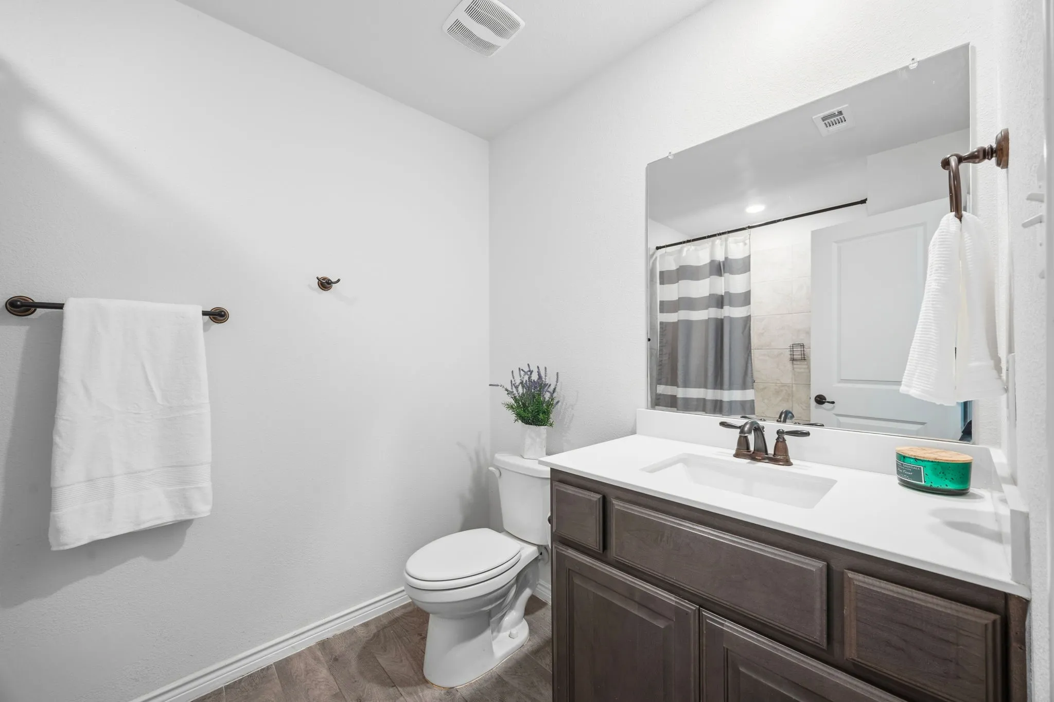 Full upstairs bathroom featuring a dark wood-finish vanity with a white countertop and undermount sink, bronze-finish faucet, and a large wall-mounted mirror