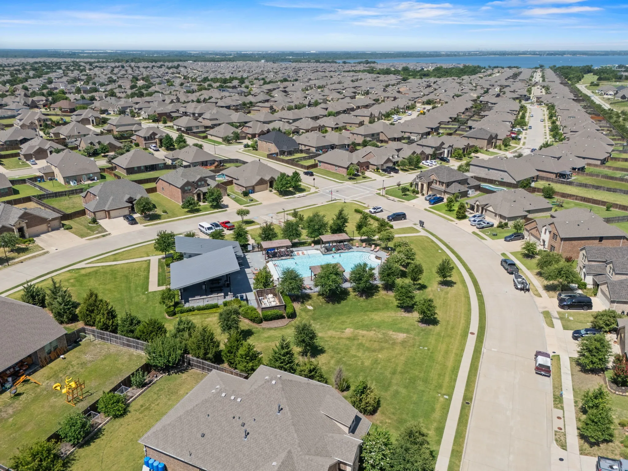 Aerial overview of a residential community featuring a central amenity area with a swimming pool and covered lounge structure