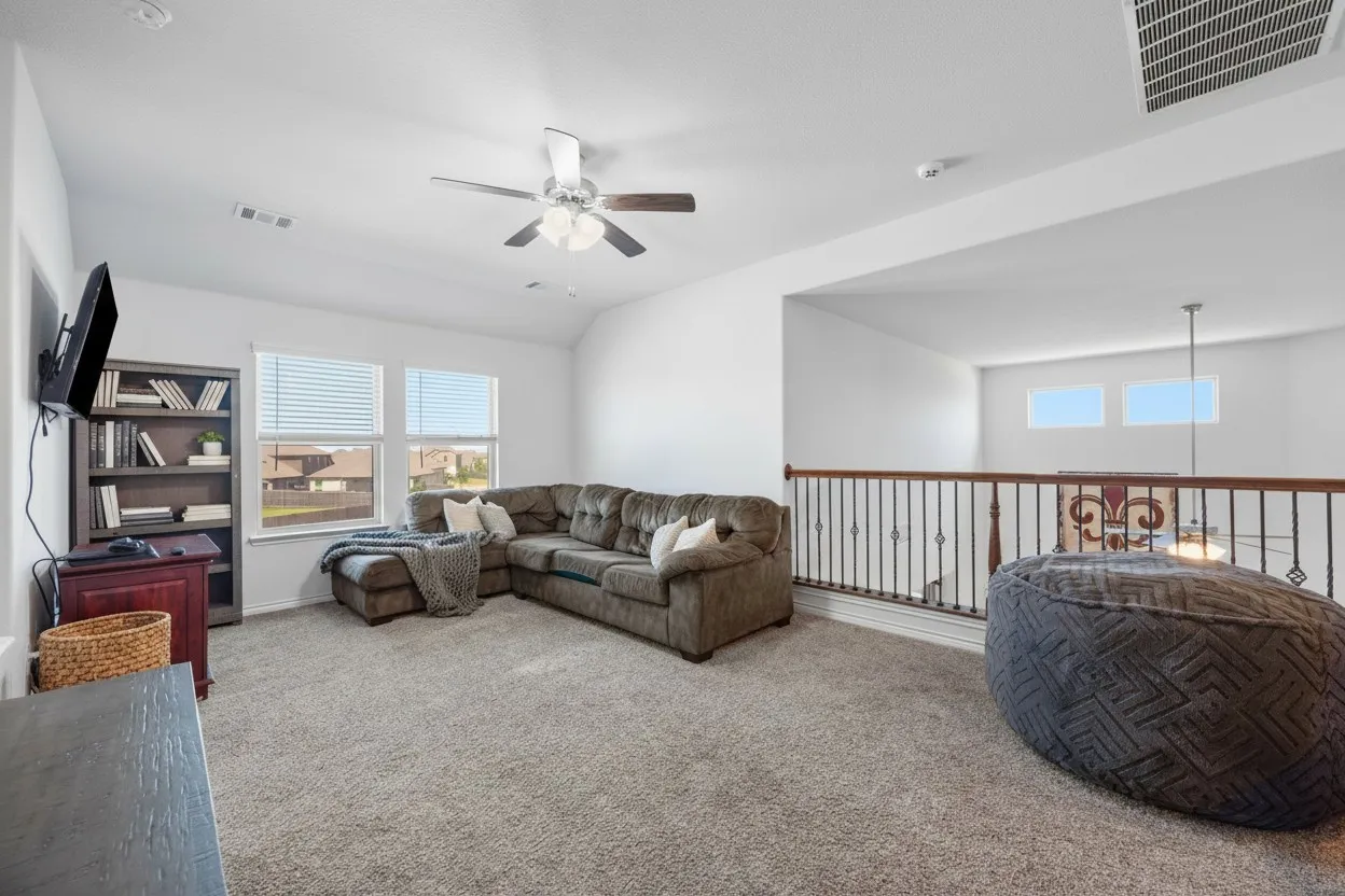 Spacious loft area featuring plush carpeting and a ceiling fan