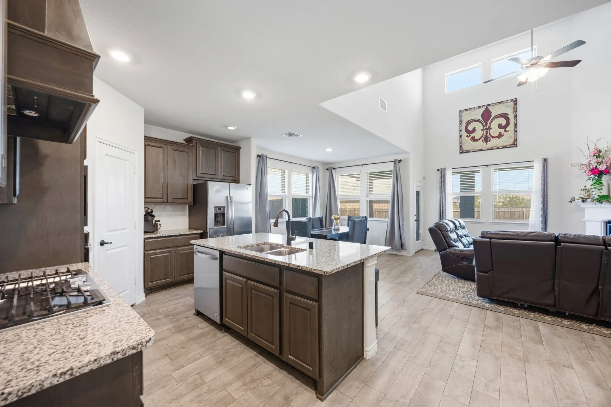 Open-concept living space featuring a kitchen island with dual sink, granite countertops, and wood-finish flooring