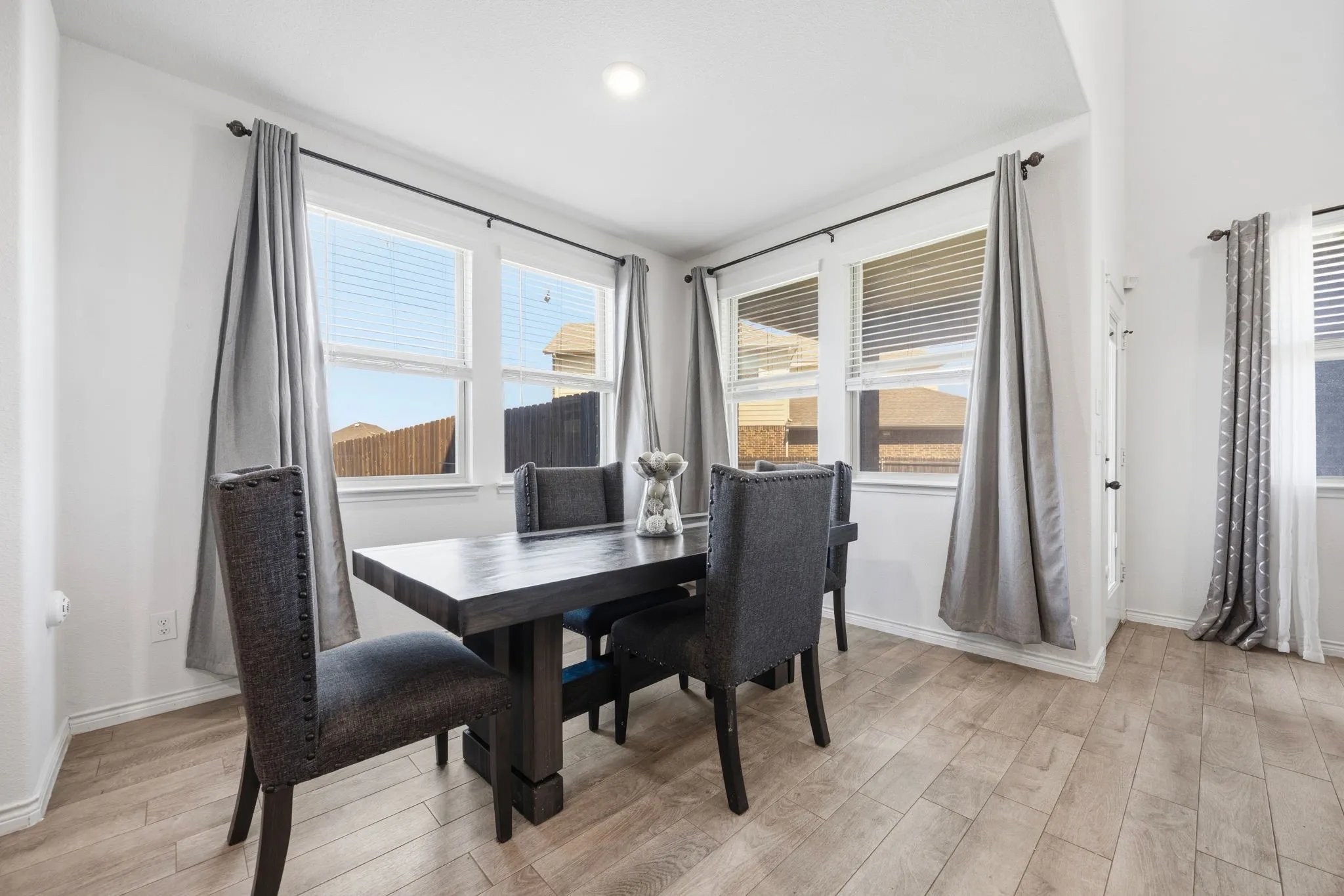 Dining area featuring wood-finish tile flooring and multiple windows with blinds