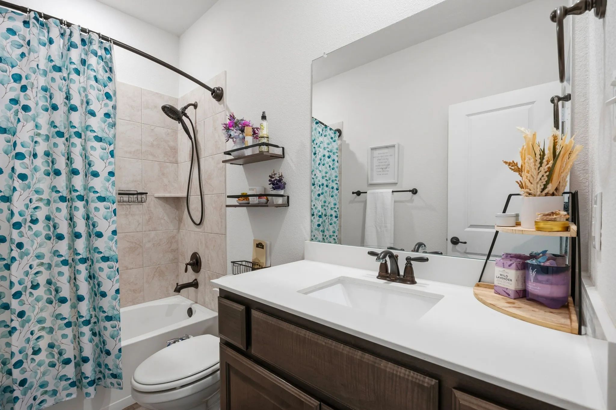 Downstairs bathroom featuring a vanity with a white countertop, an integrated sink, bronze hardware, and dark wood-finish cabinetry