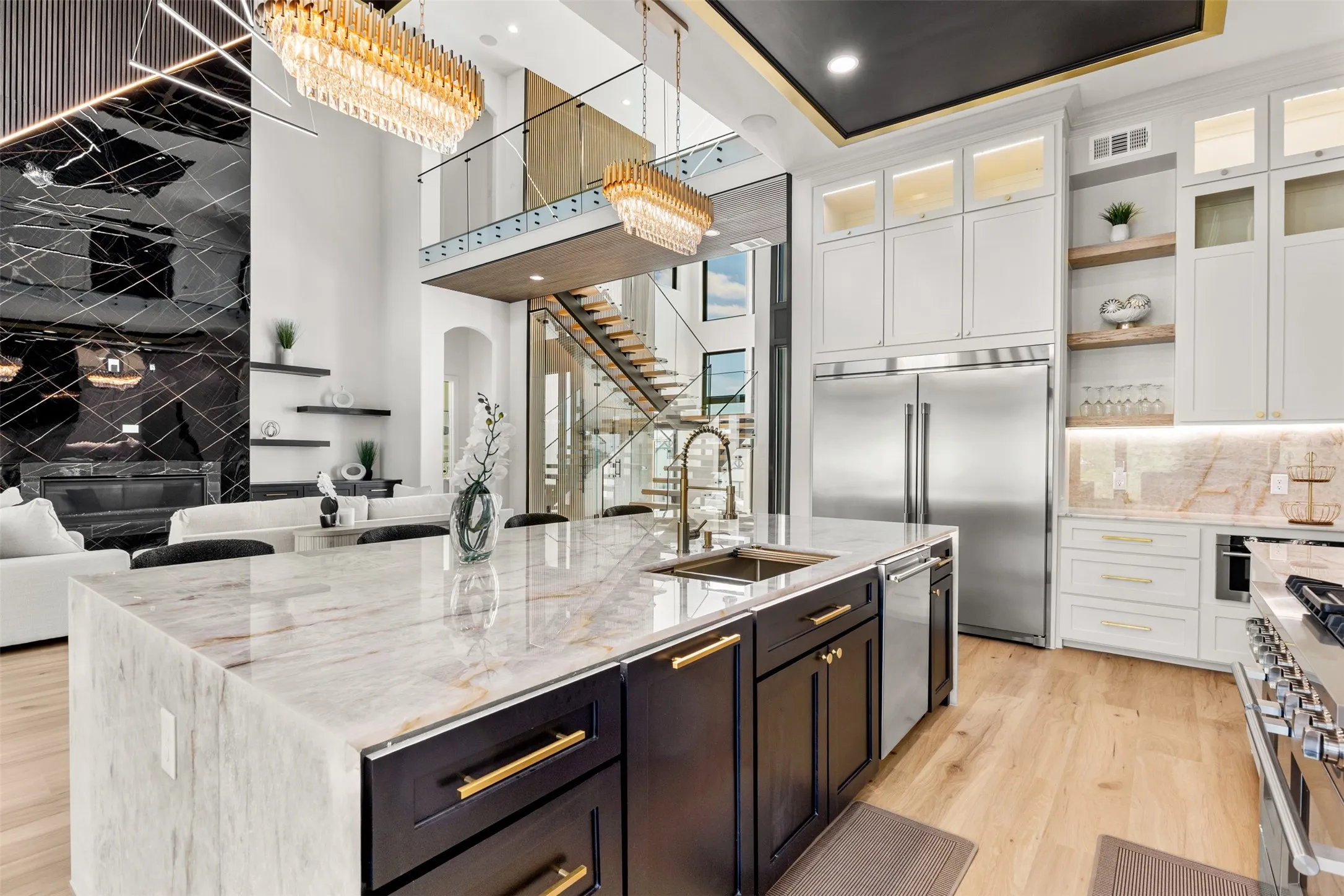 Spacious kitchen island featuring a waterfall countertop, integrated sink, and dark wood cabinetry with gold-tone hardware